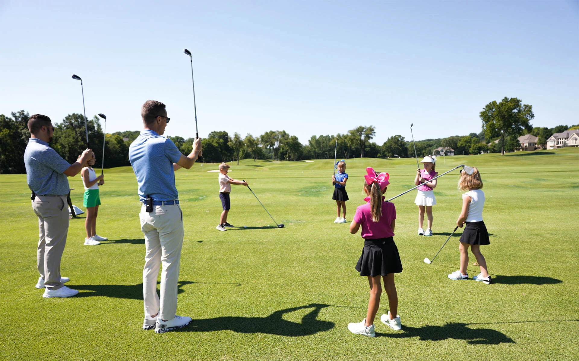 Invited Crush It! Junior Golf Clinic in action: Expert coaches guiding young children in learning the golf grip on an Invited Club driving range