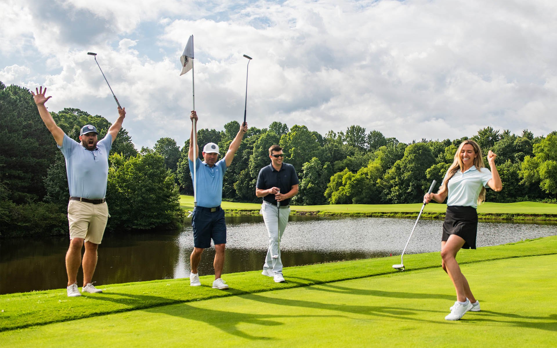 Four adult golfers celebrate a successful birdie putt during Game On Golf Lessons, showcasing the joy and success of our program at Invited country club locations nationwide.