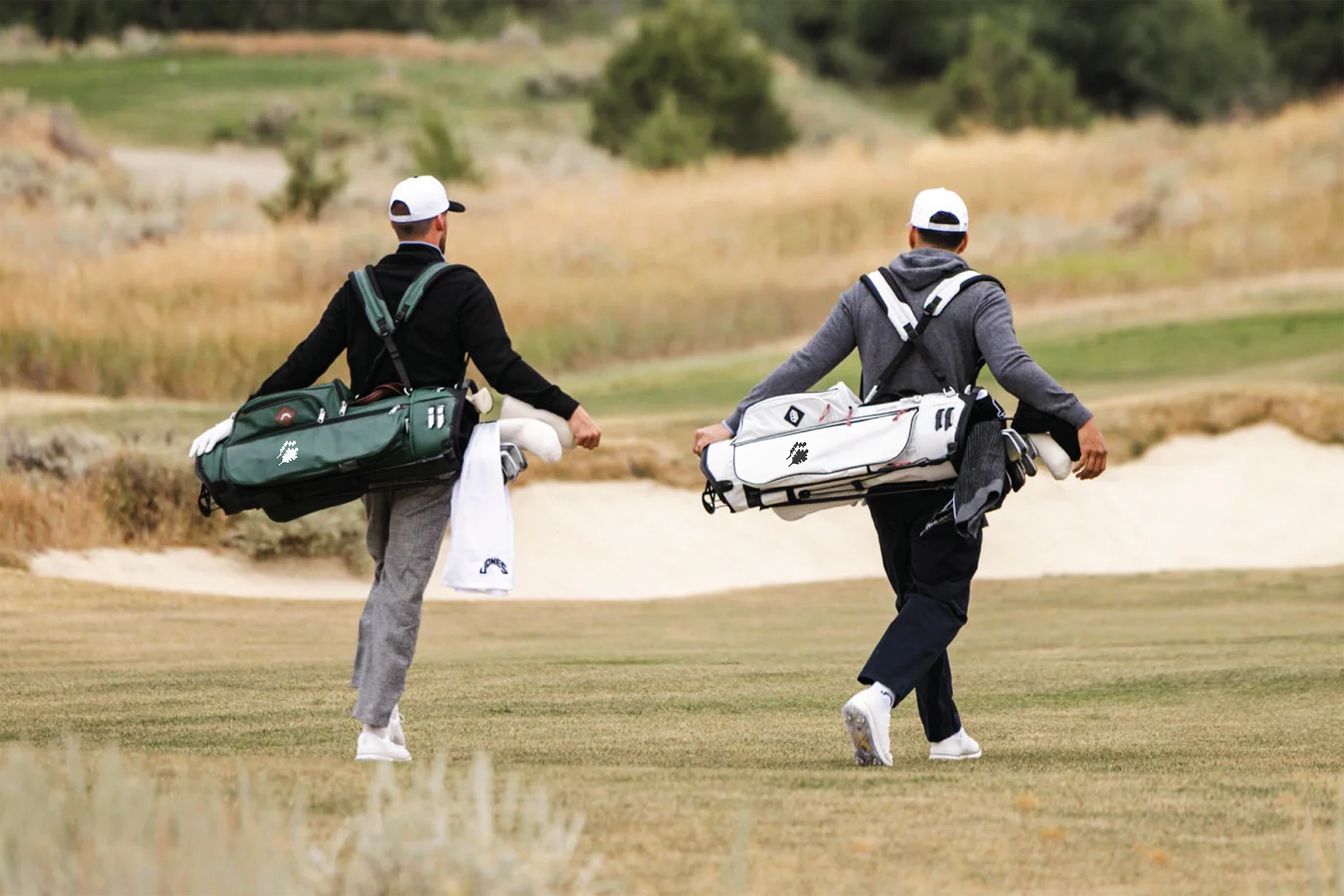 Two golfers walking on course carrying their bags