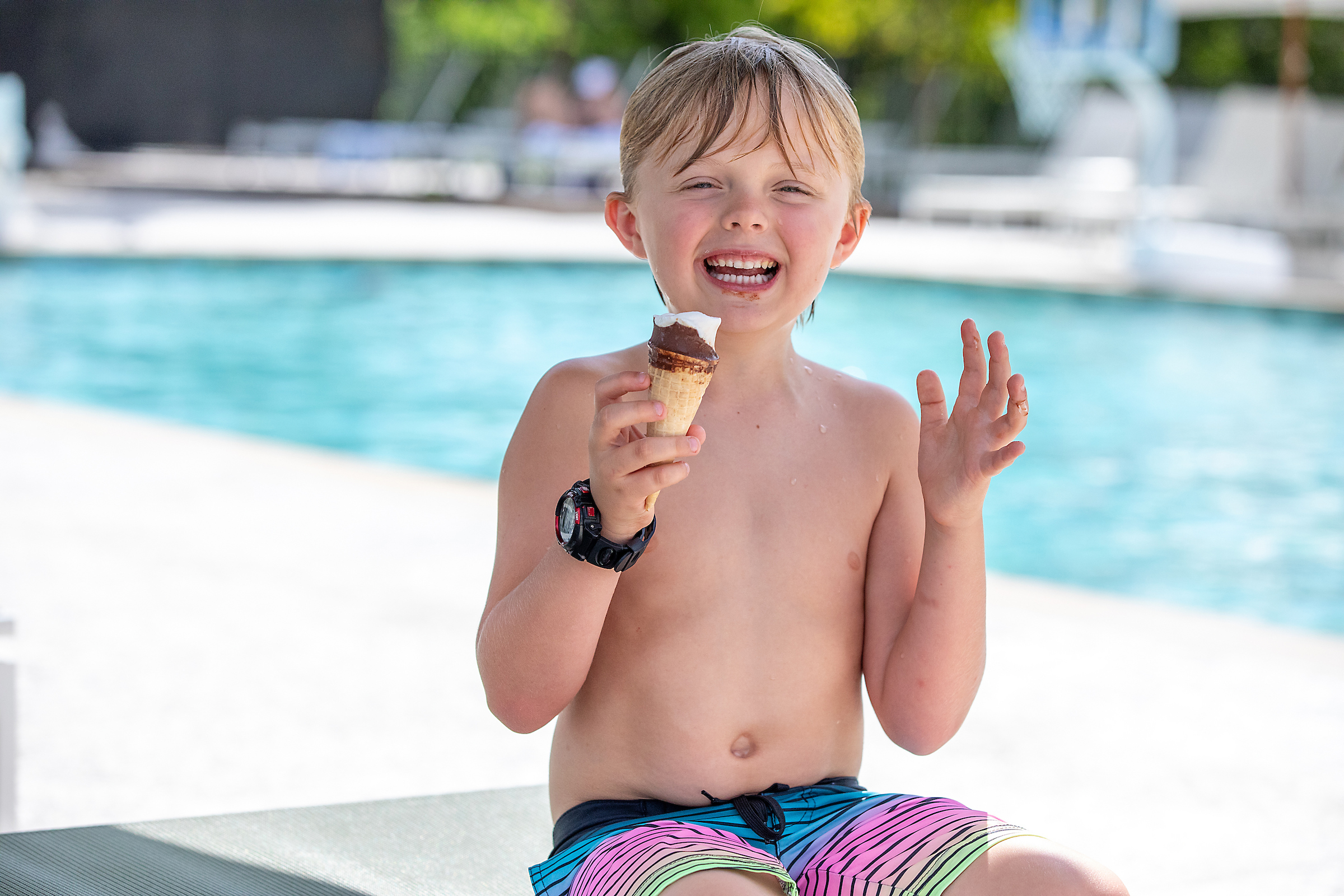 Child enjoying an ice cream cone by the pool
