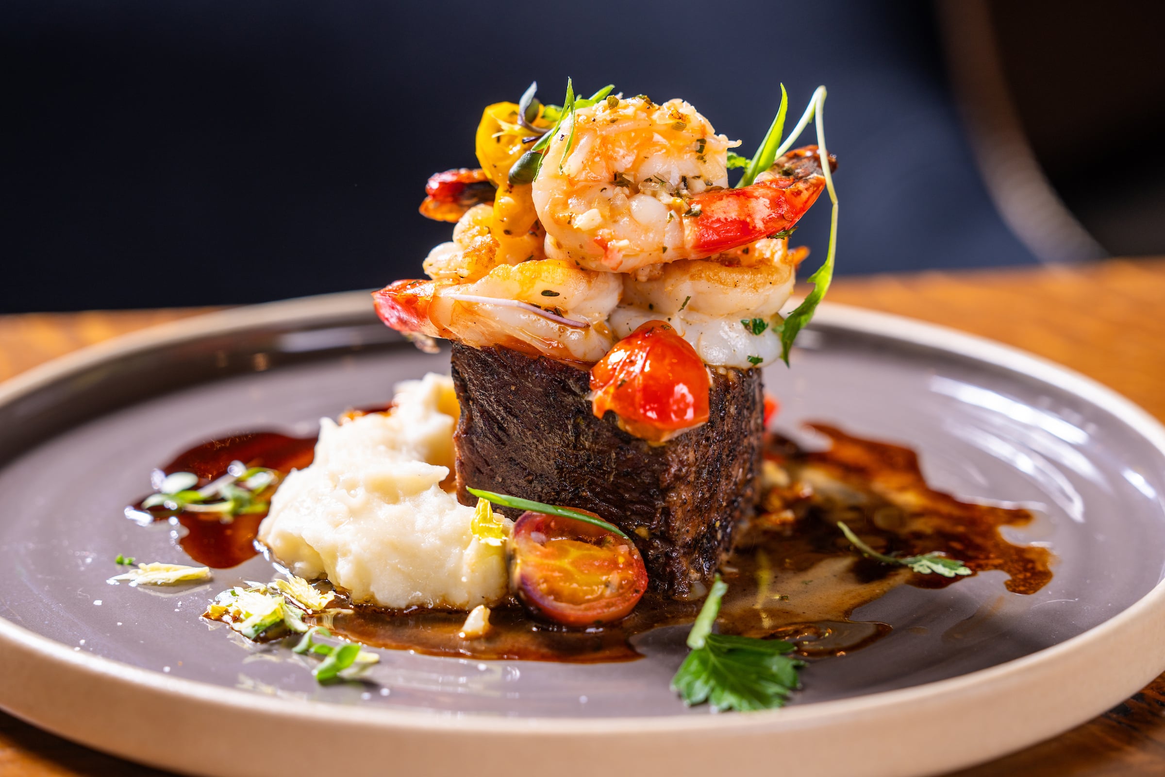 Artistically arranged steak and shrimp dish and garnish.