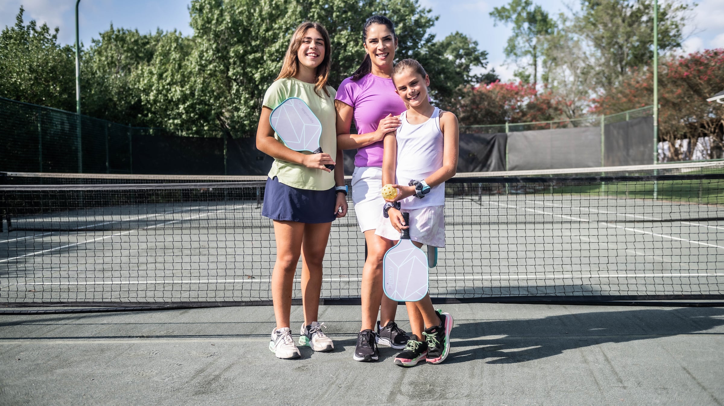 Mother and two daughters posing with pickleball paddles