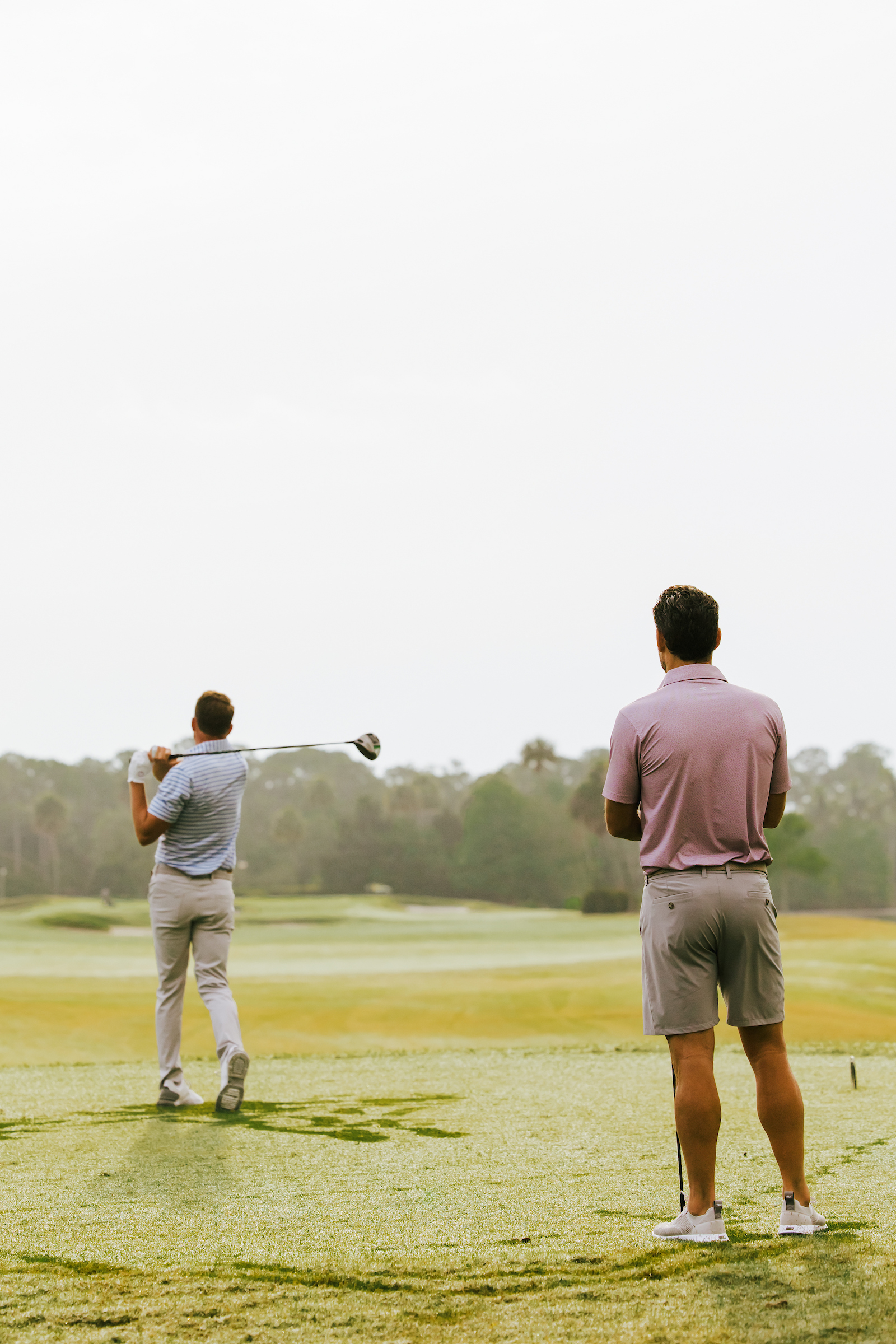 2 guys hitting a golf ball from the tee box