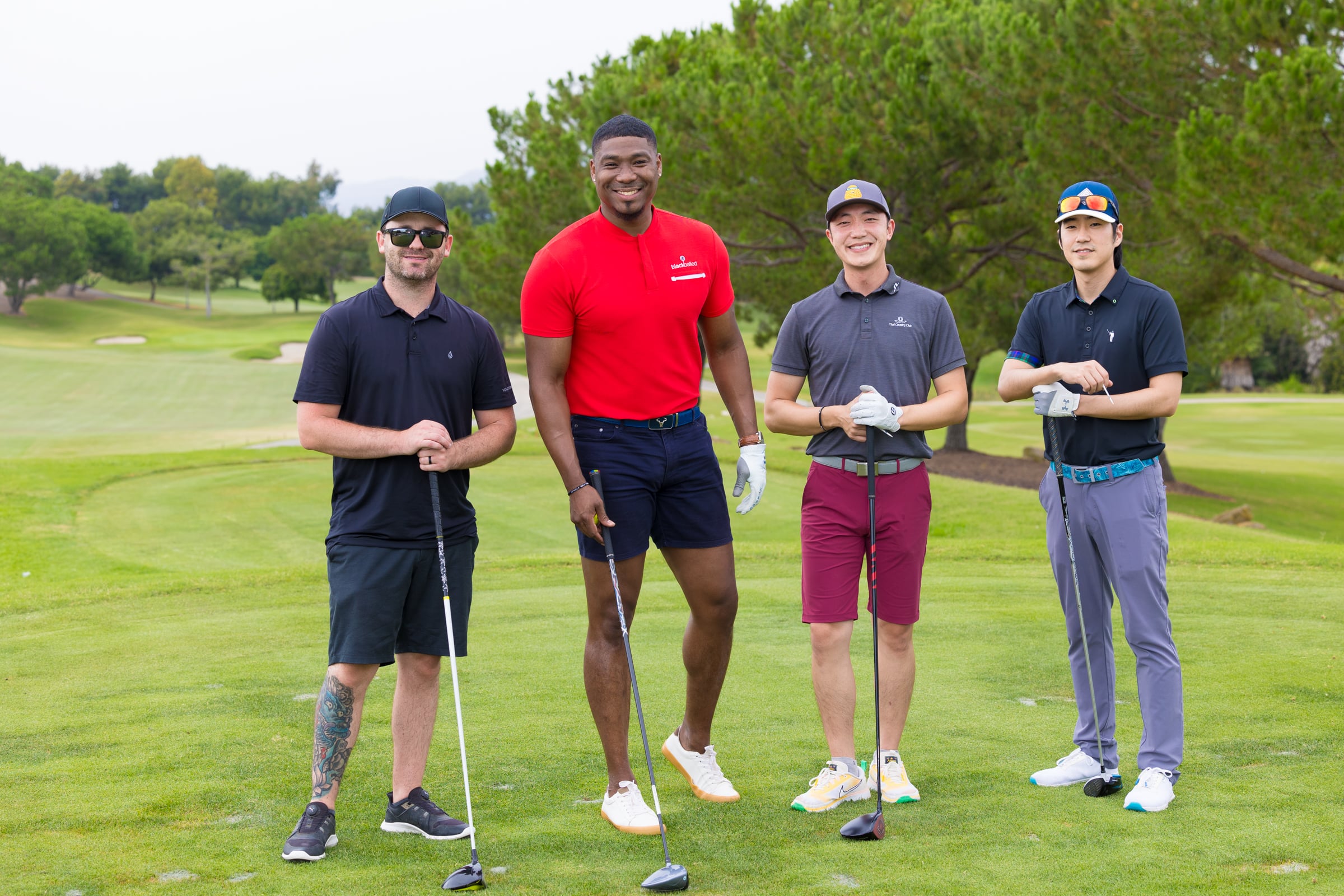 4 guys standing on a golf course
