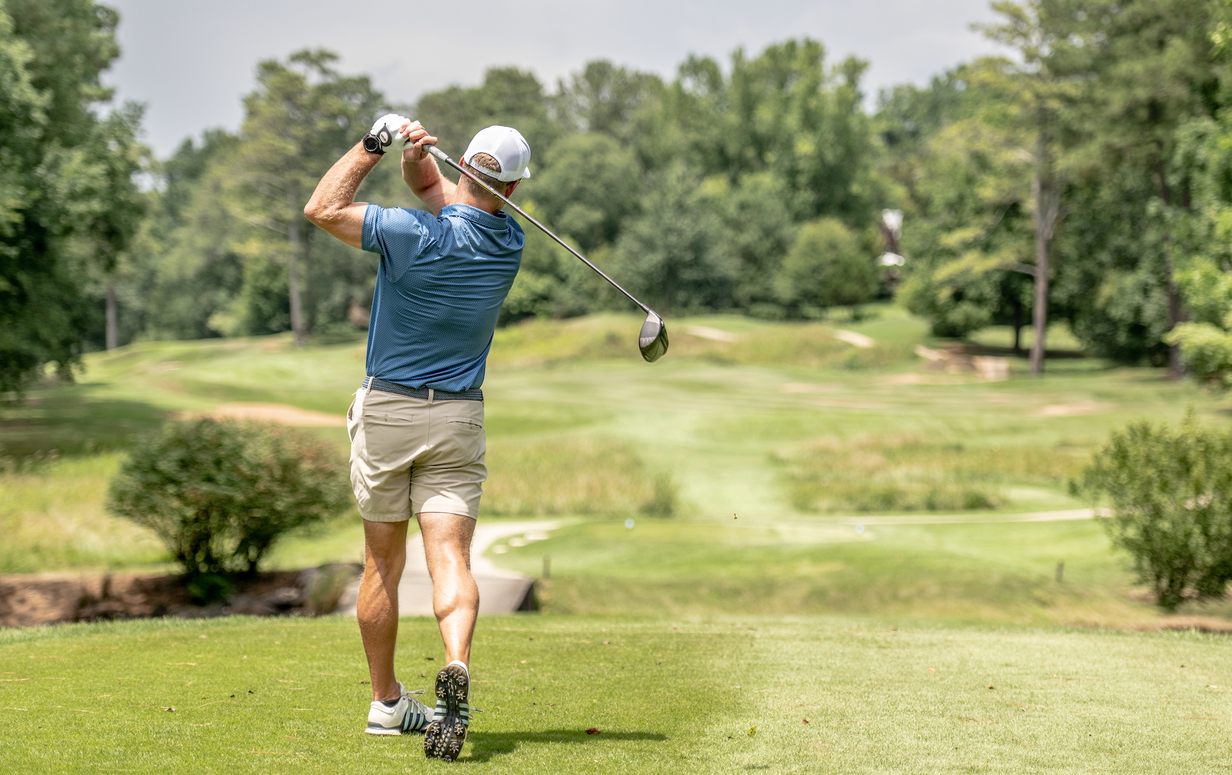 Golfer hitting a golf ball down the fairway