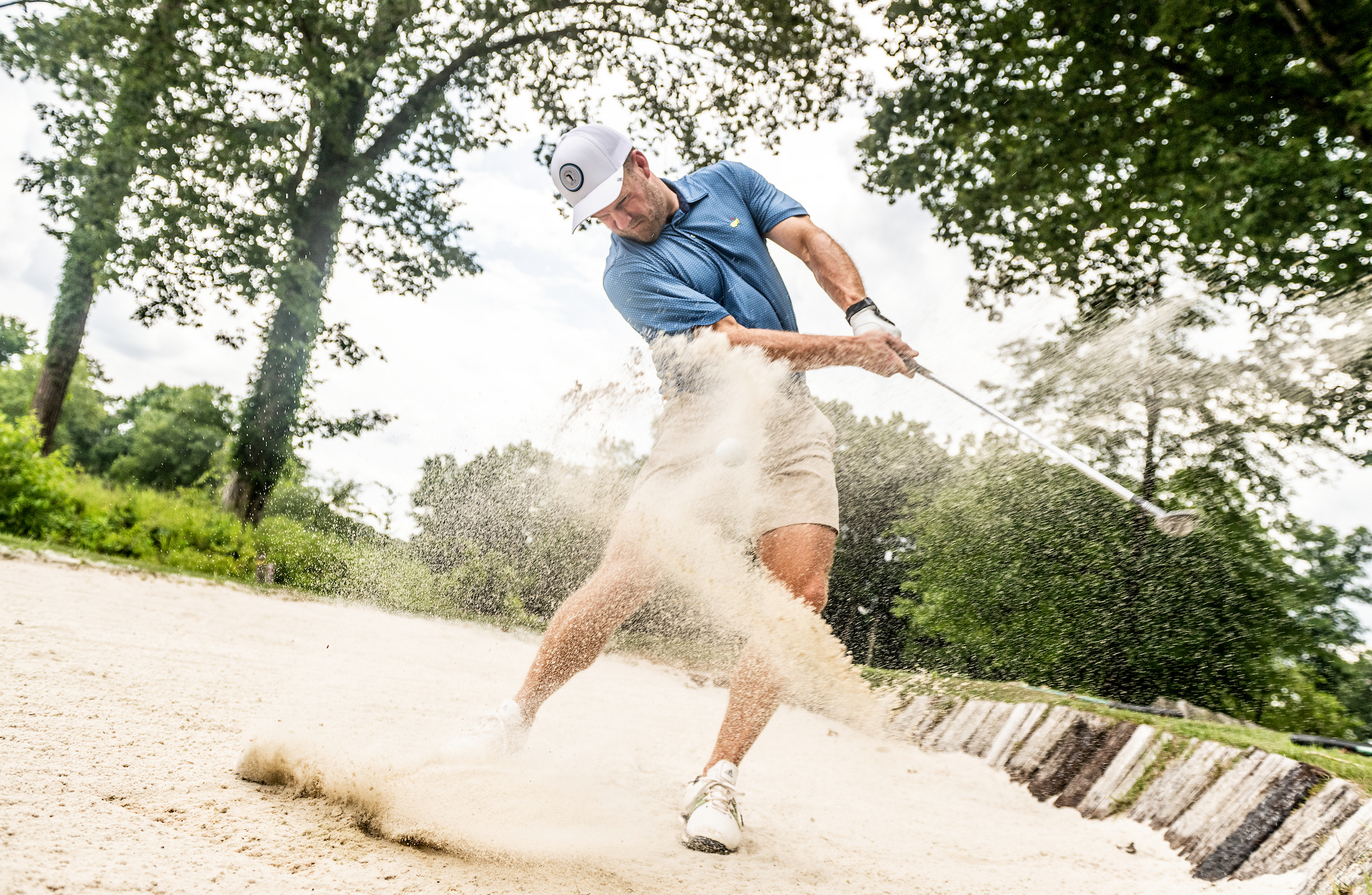 Golfer swinging in sand bunker