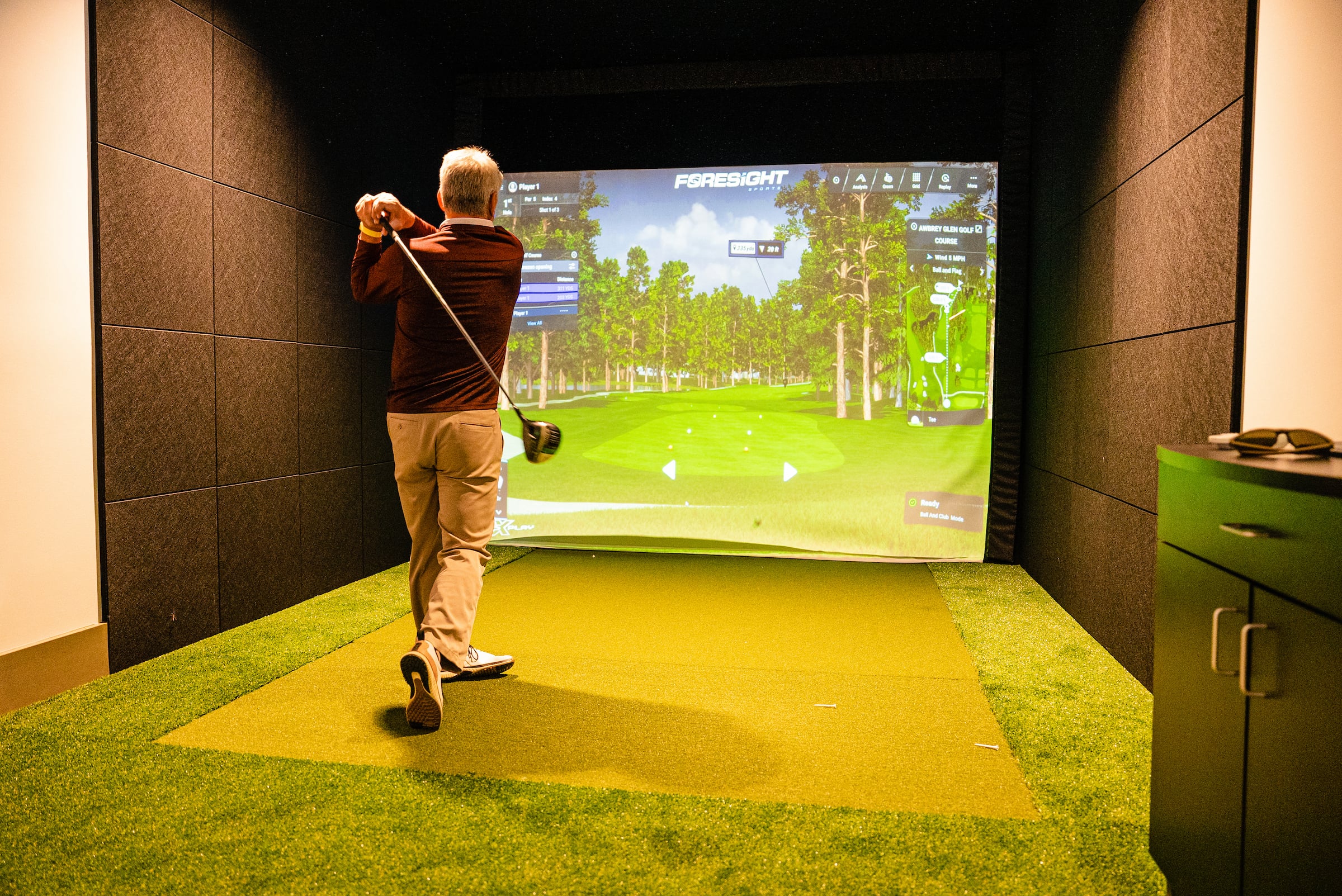 Man swinging a golf club in a Swing Suite Lounge