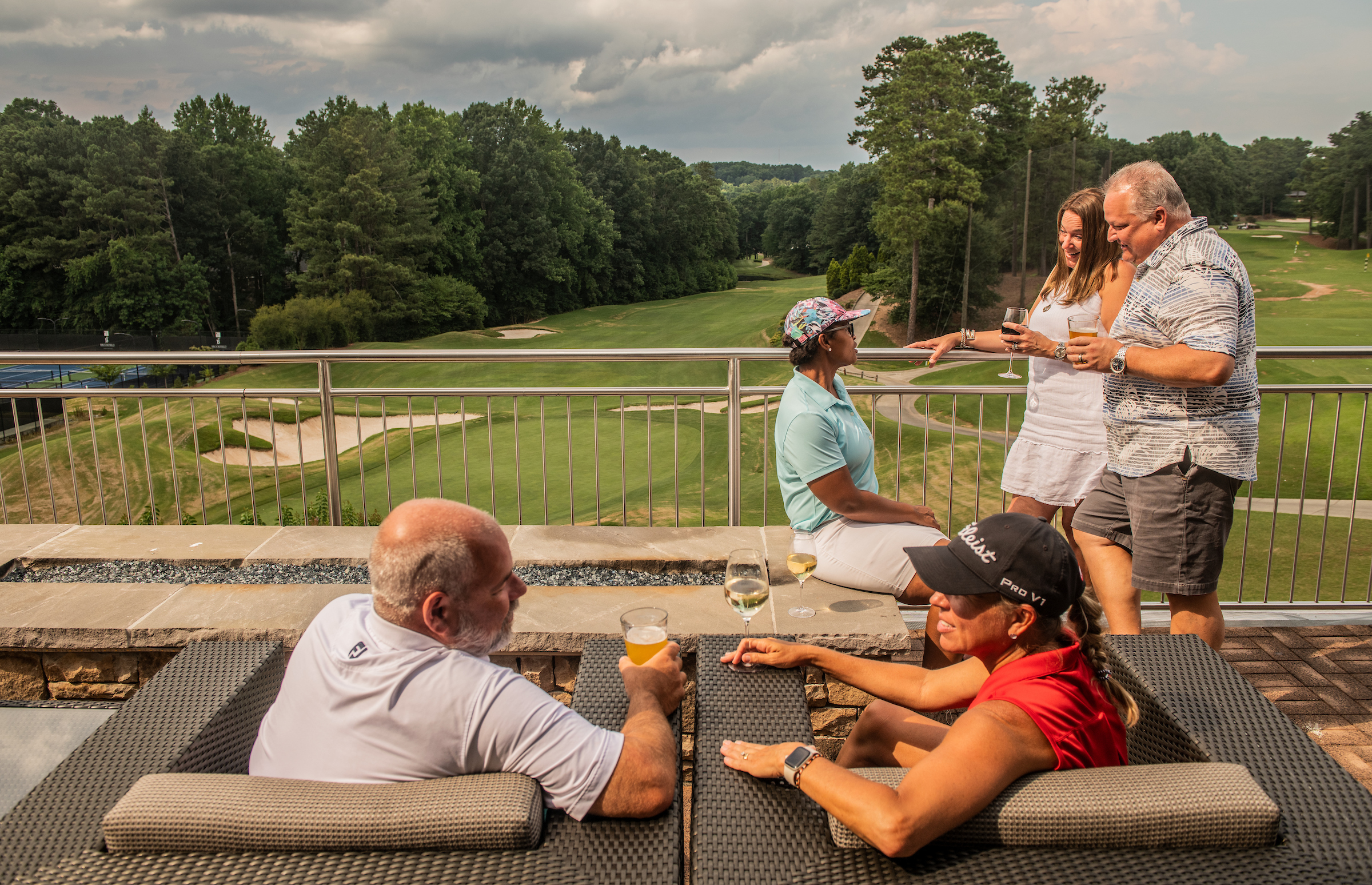 Members dining and drinking of a patio overlooking a golf course