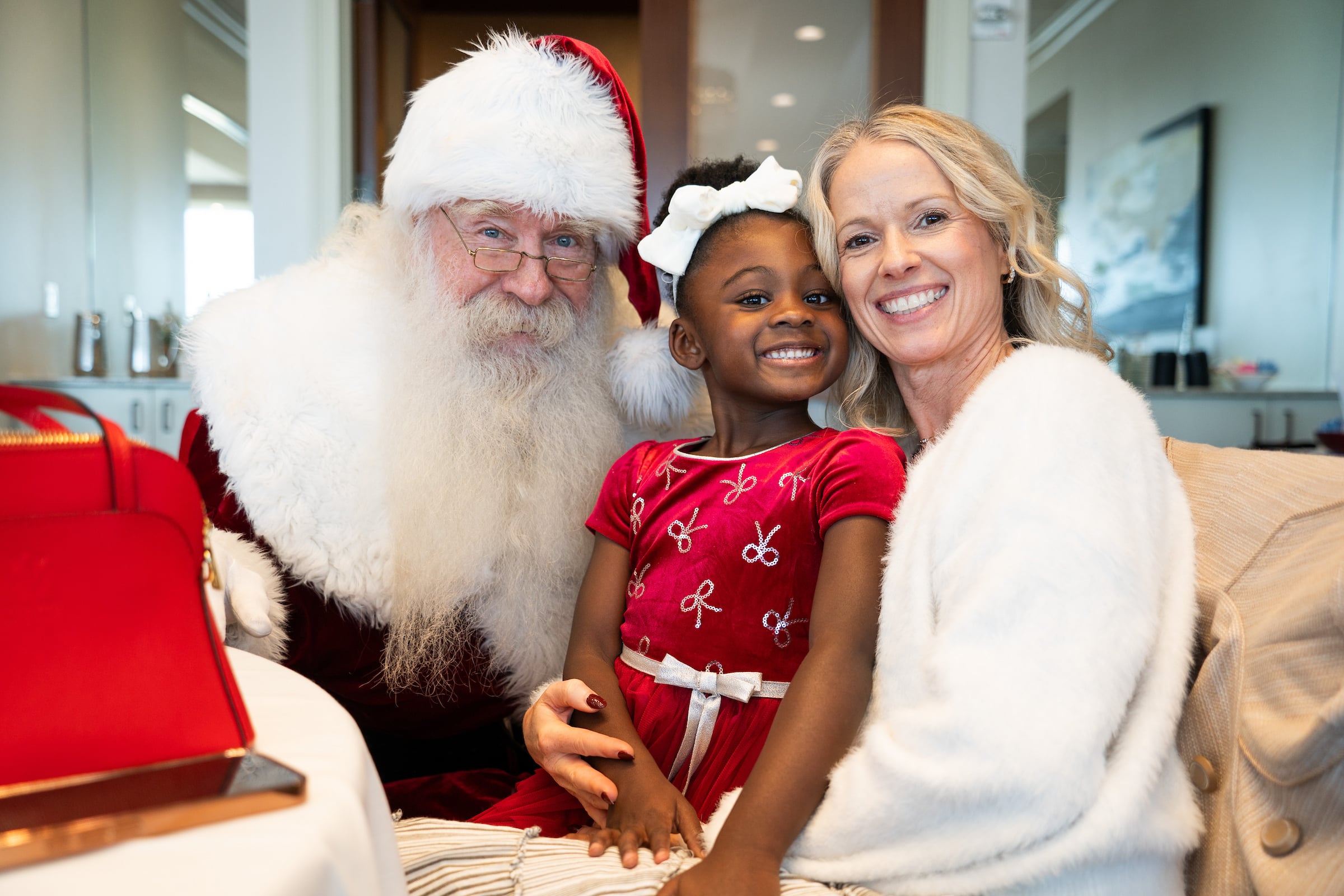 Young girl smiling with santa and her mother