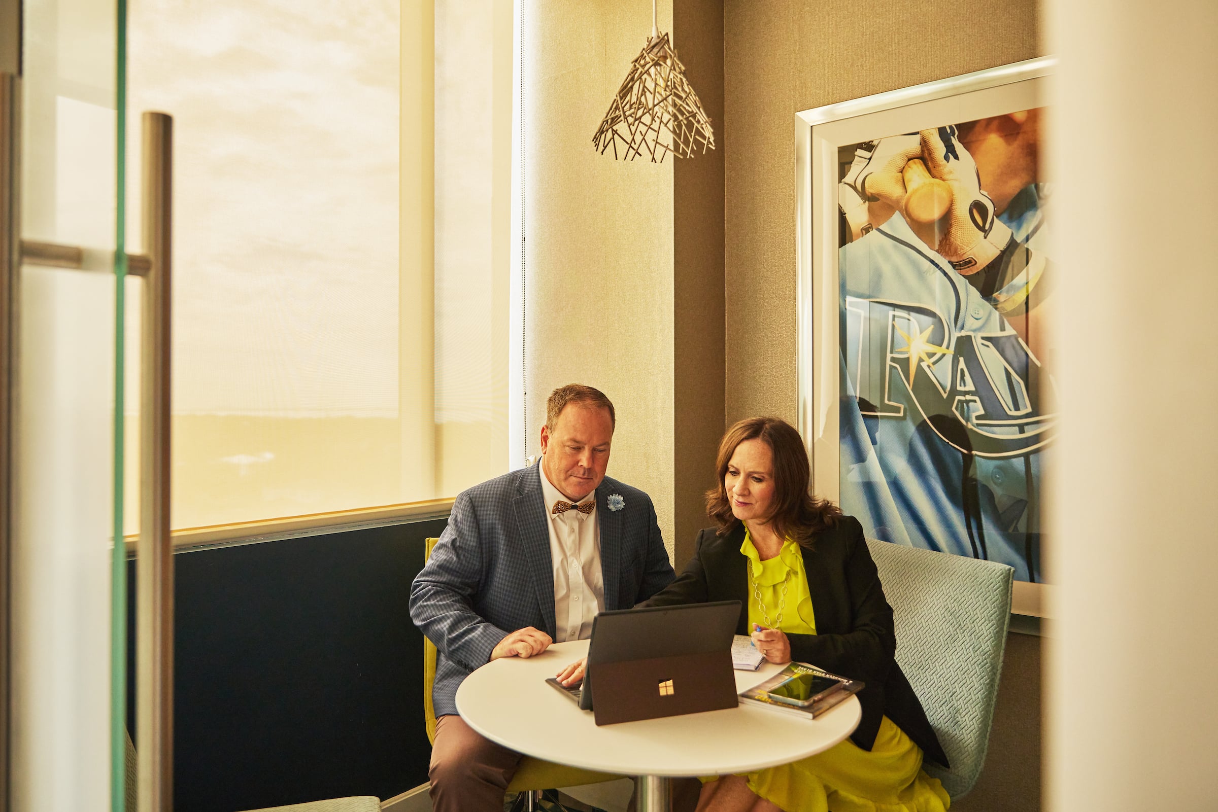 Man & woman seated at small round table with a computer