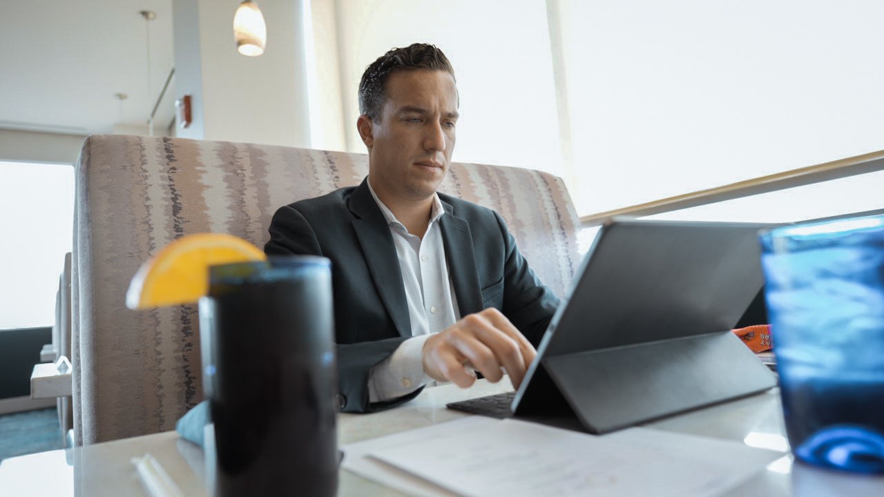 Man seated working on a computer with a glass of tea
