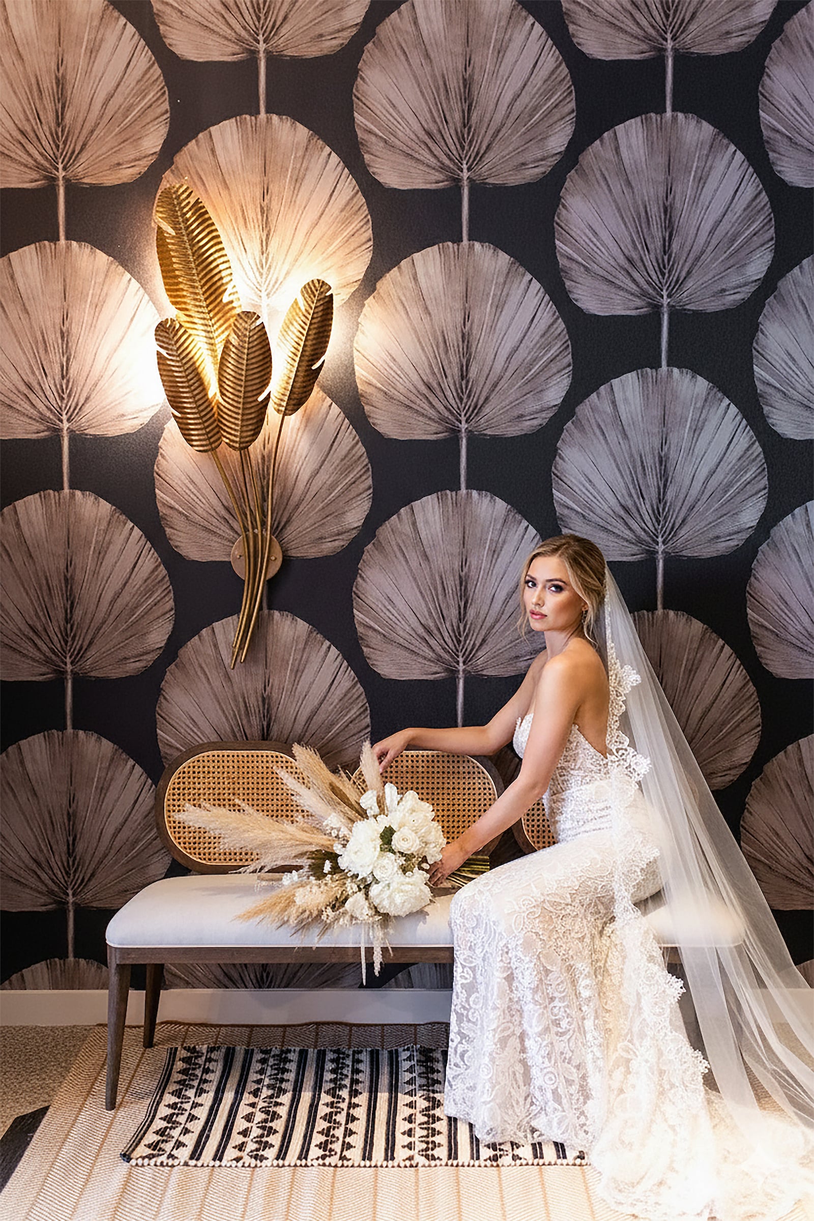 Bride in a lace wedding gown seated on bench with her bouquet