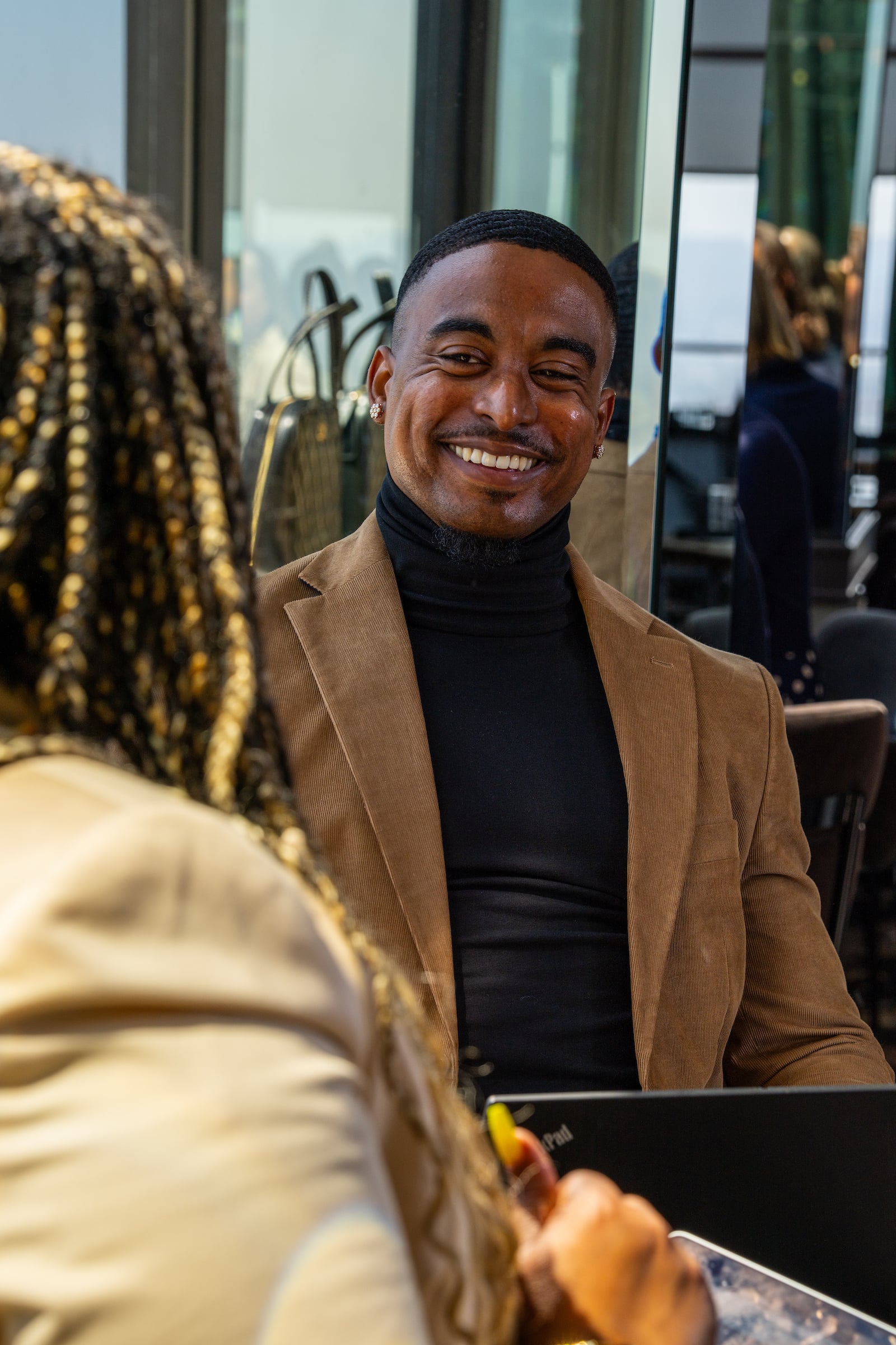 Man seated & smiling at another person