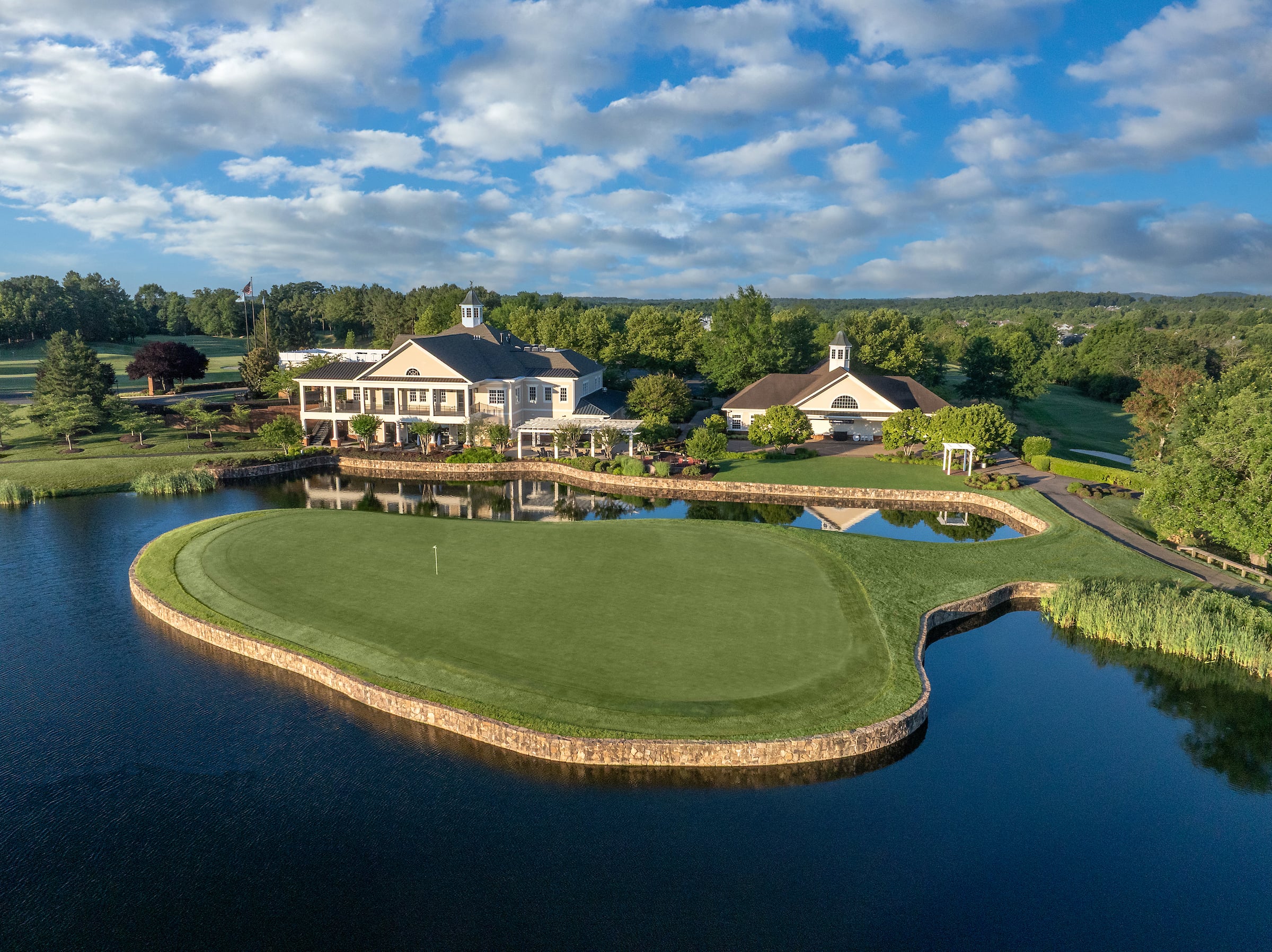 view of a golf course green and clubhouse surrounded by a lake