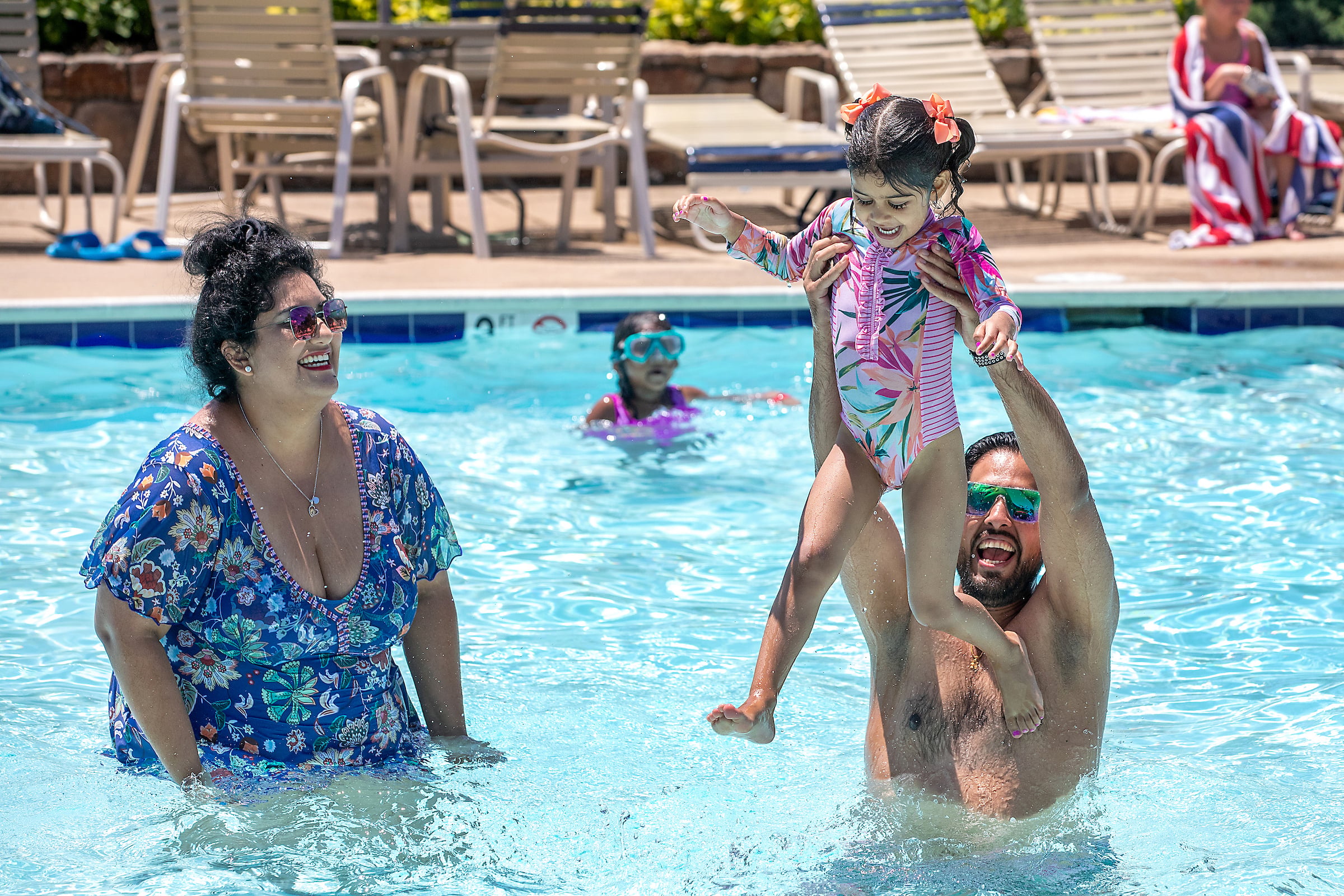 Mom and Dad playing in the pool with their daughter