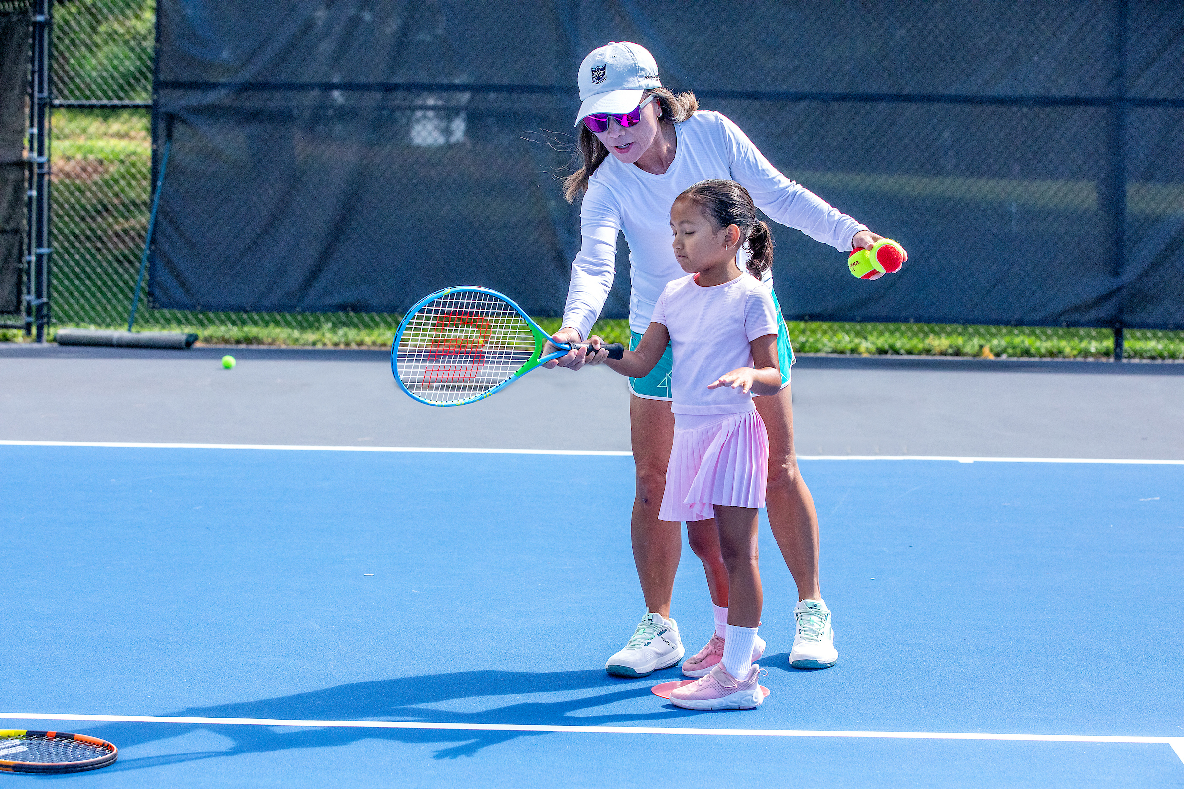 female instructor teaching tennis to young girl