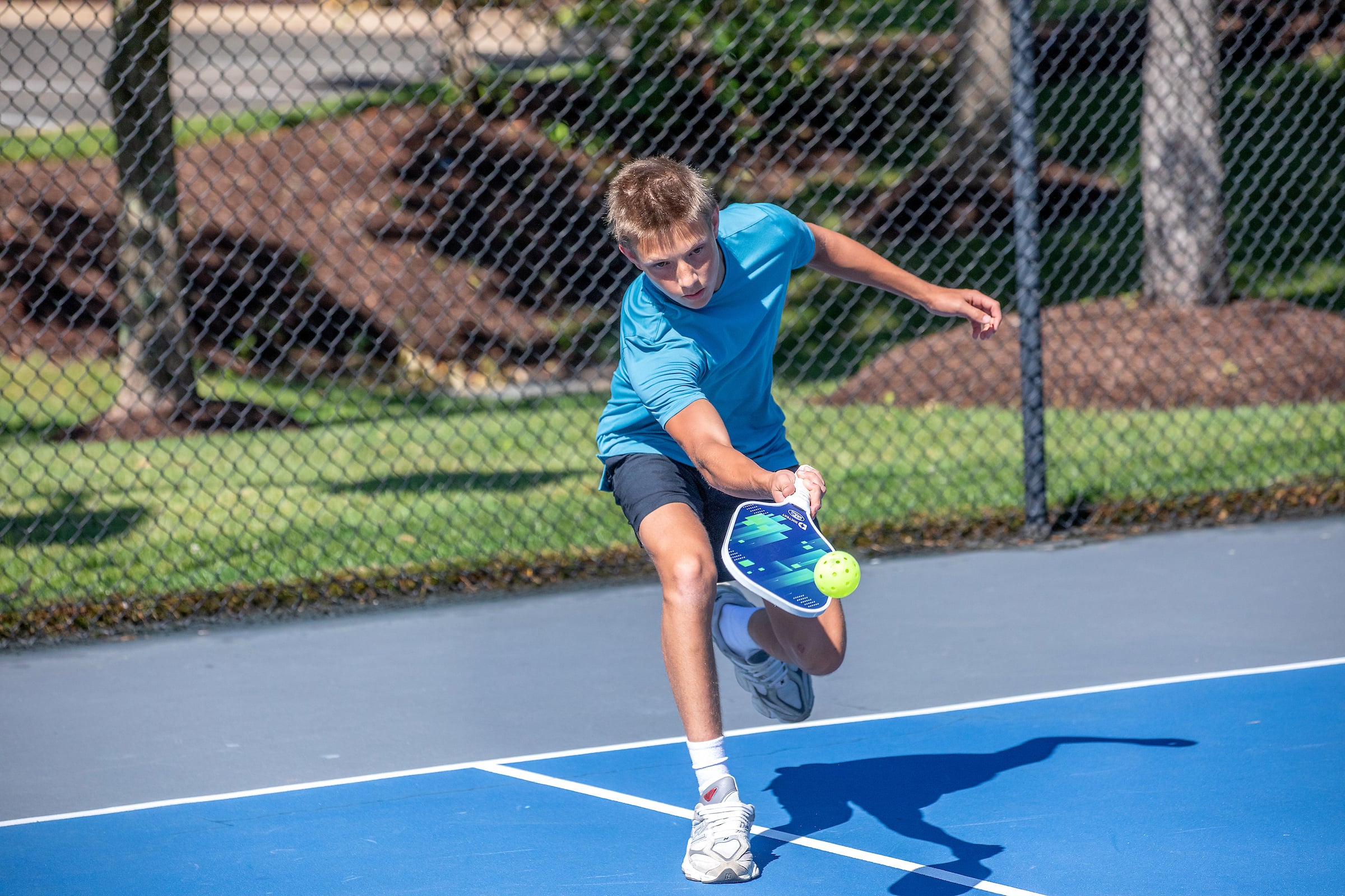 a young male teen playing pickleball
