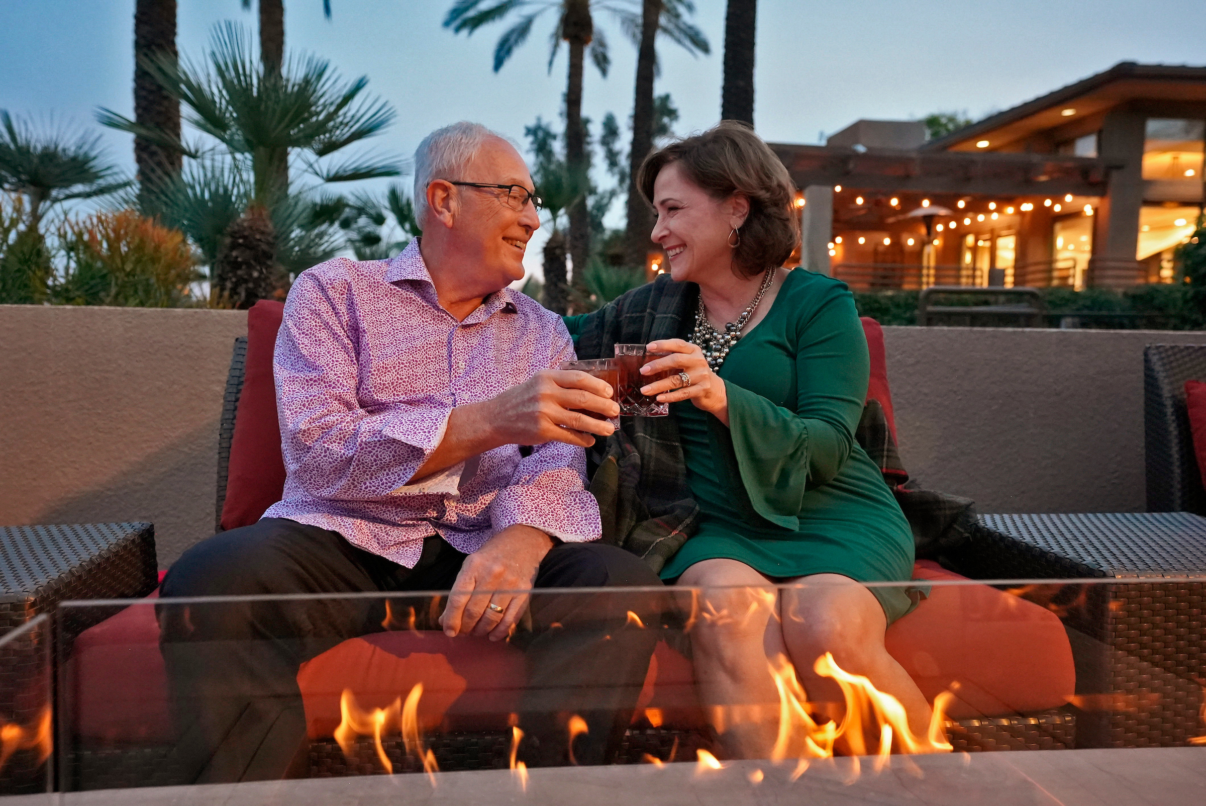 couple cheering drinks by a fire pit