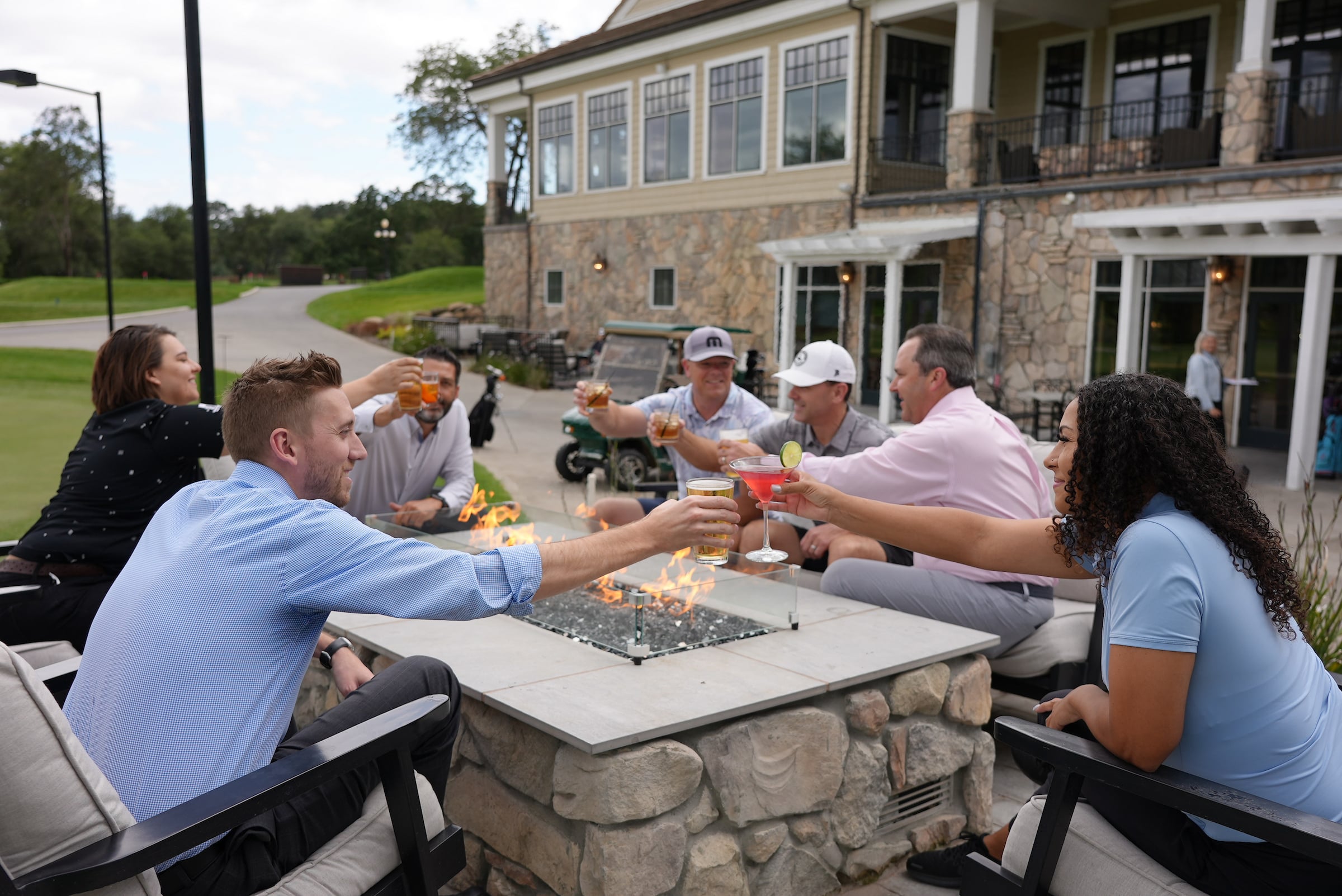 adults gathered around a firepit enjoying drinks