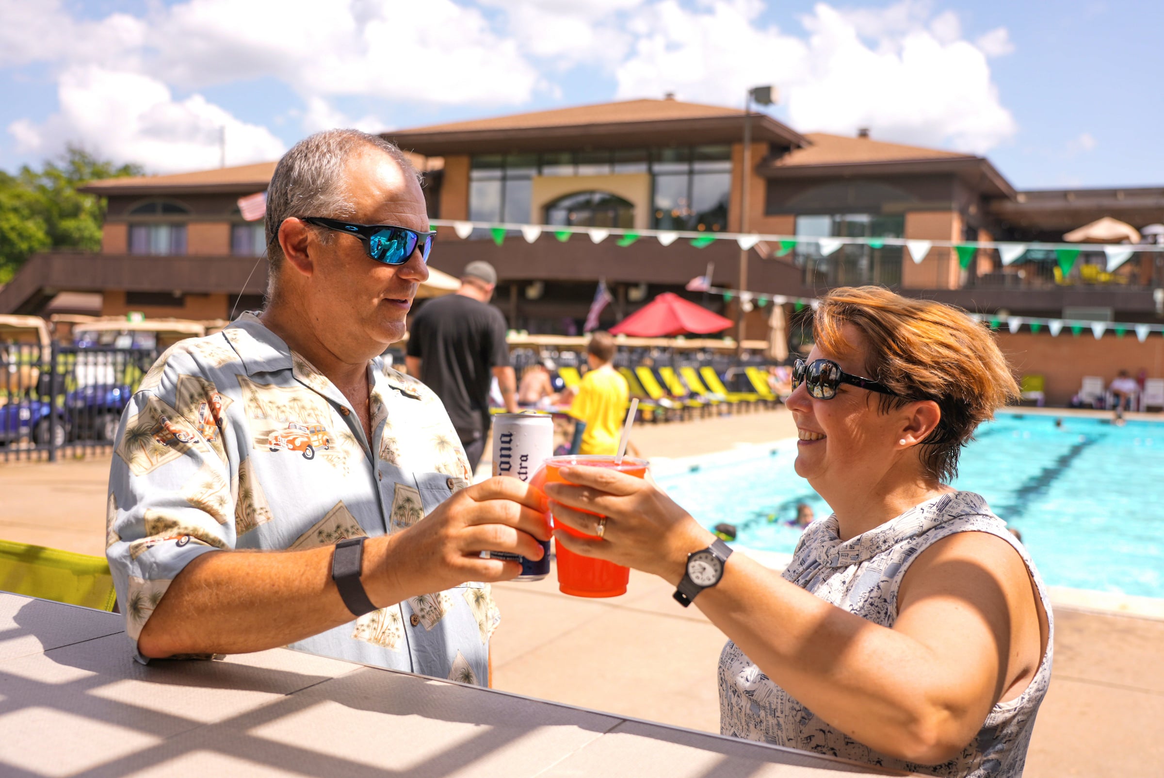 Couple cheering their drinks by the pool
