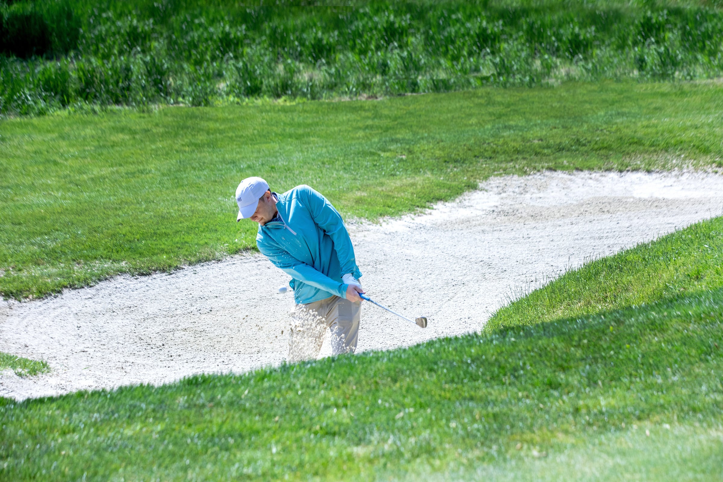 Golfer hitting ball in the bunker.