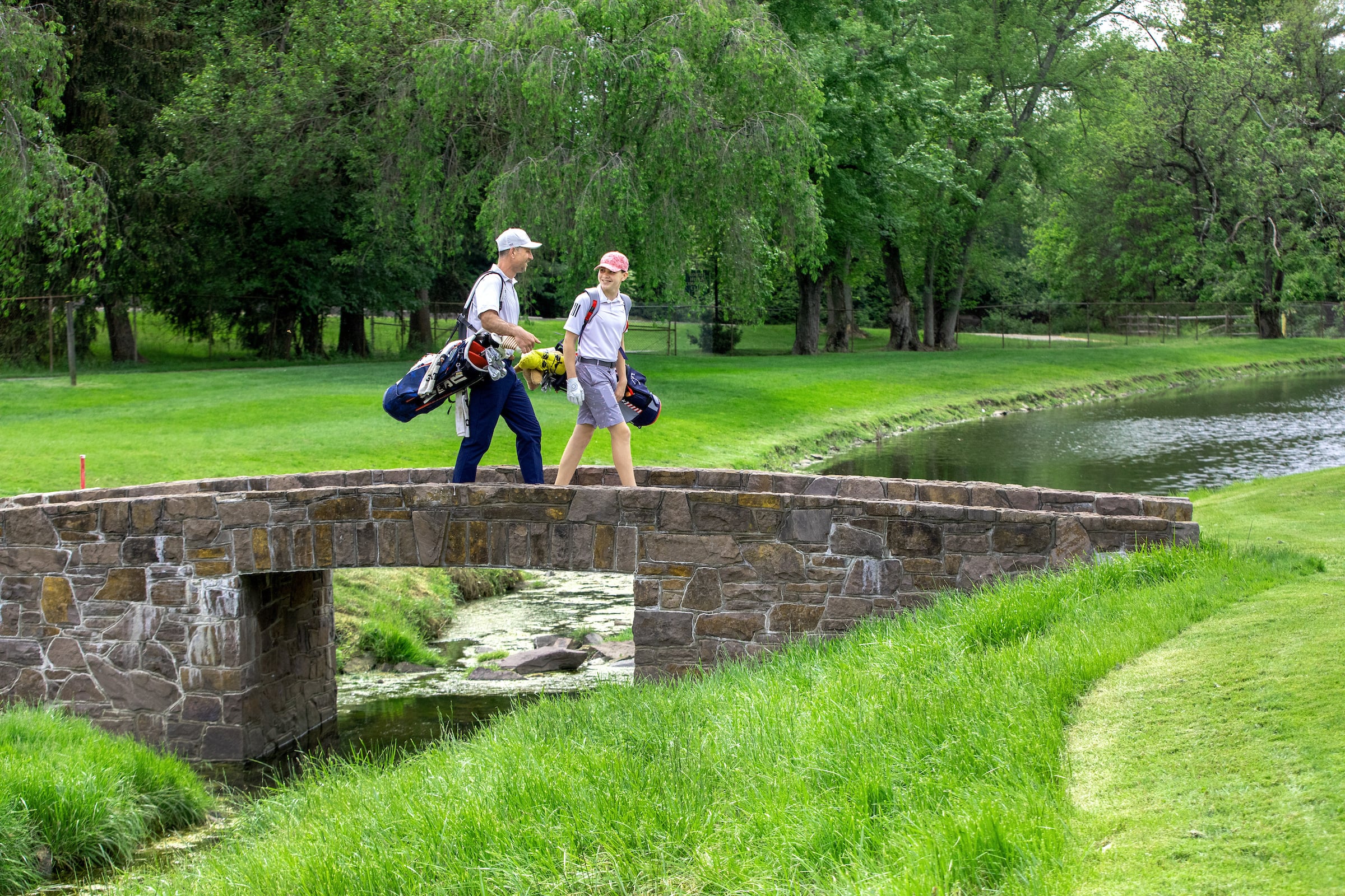 Two golfers walking over a bridge