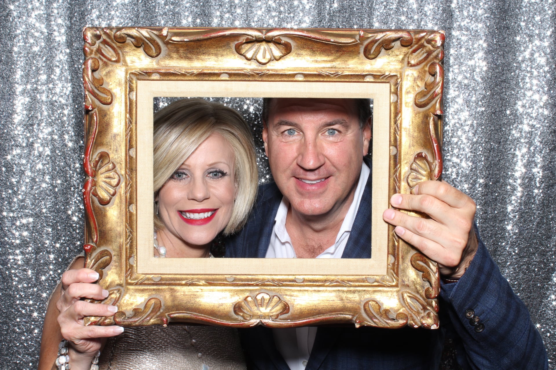 A Couple posing for picture behind a picture frame