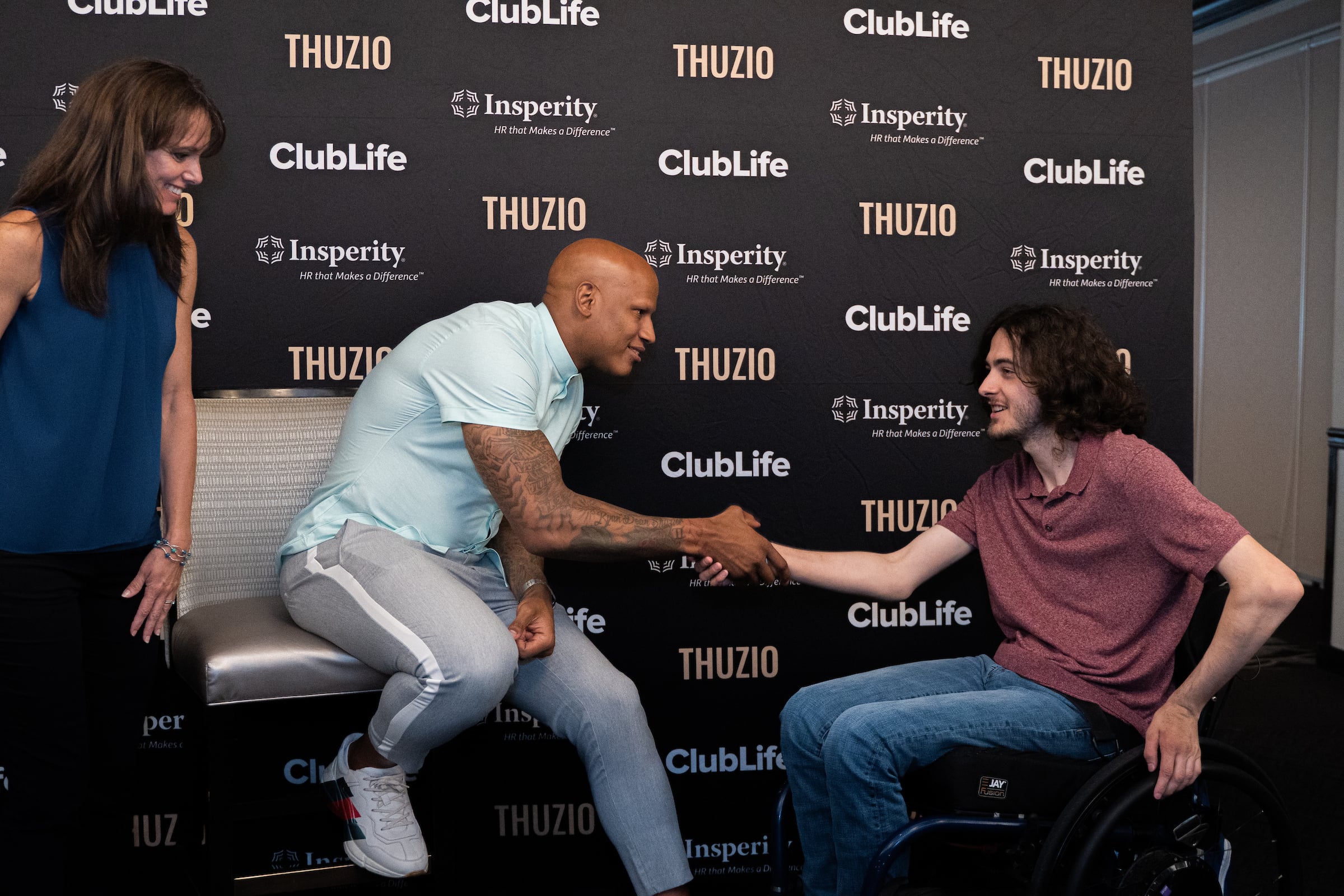Rivers Club private event with a woman standing, a seated man greeting a man in a wheelchair