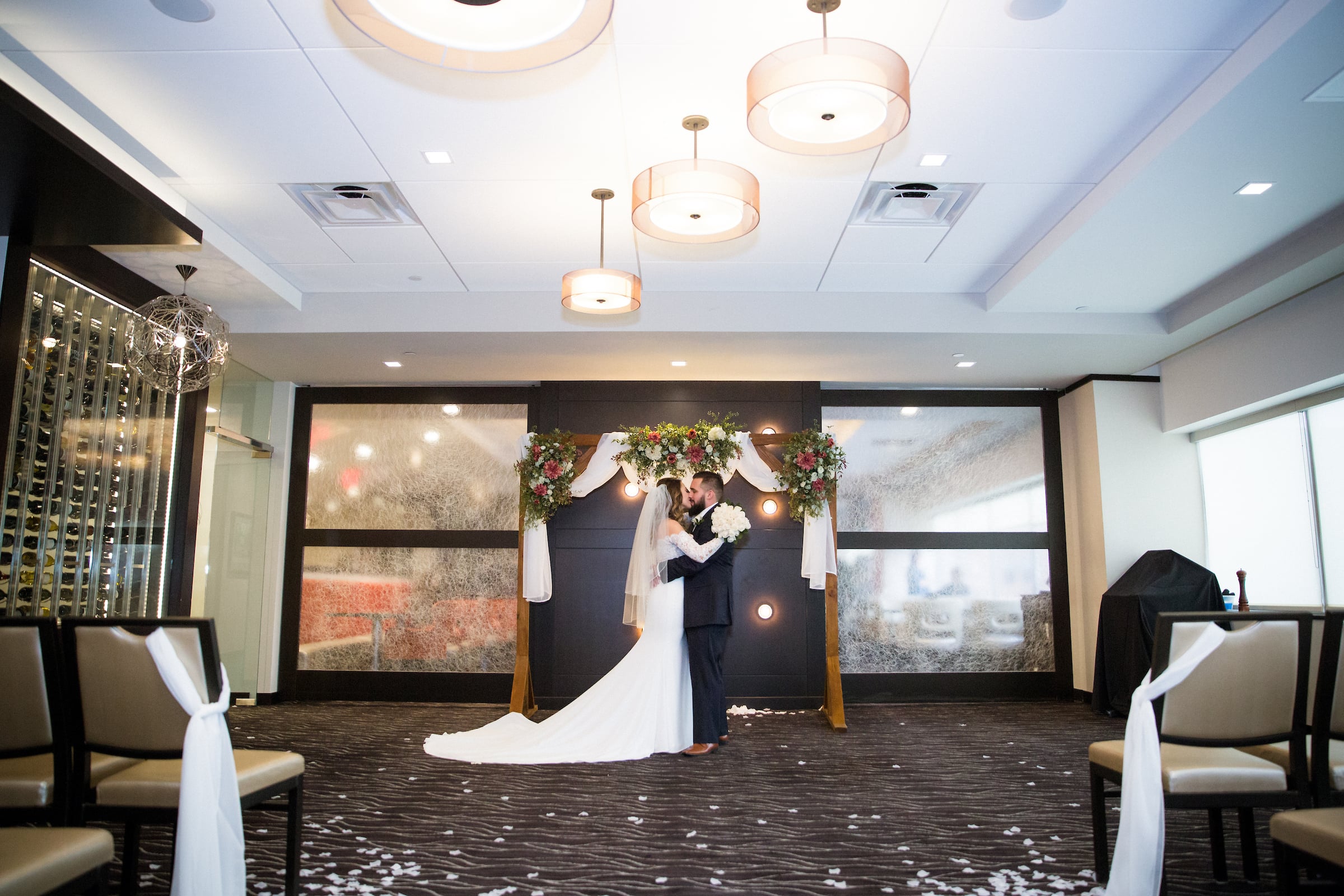 Bride & Groom standing in front of the ceremony arch kissing