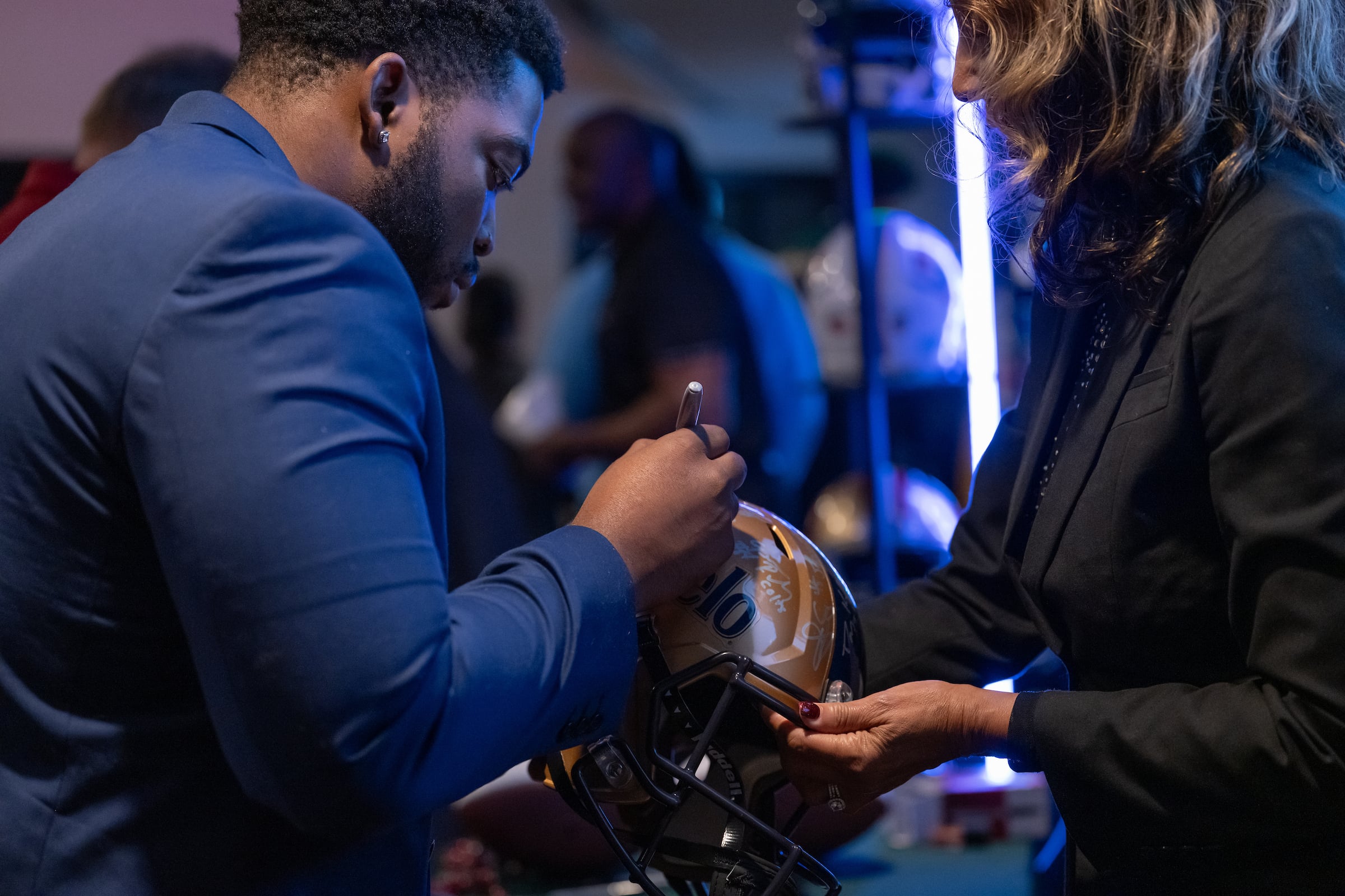 Man signing a helmet at a private event