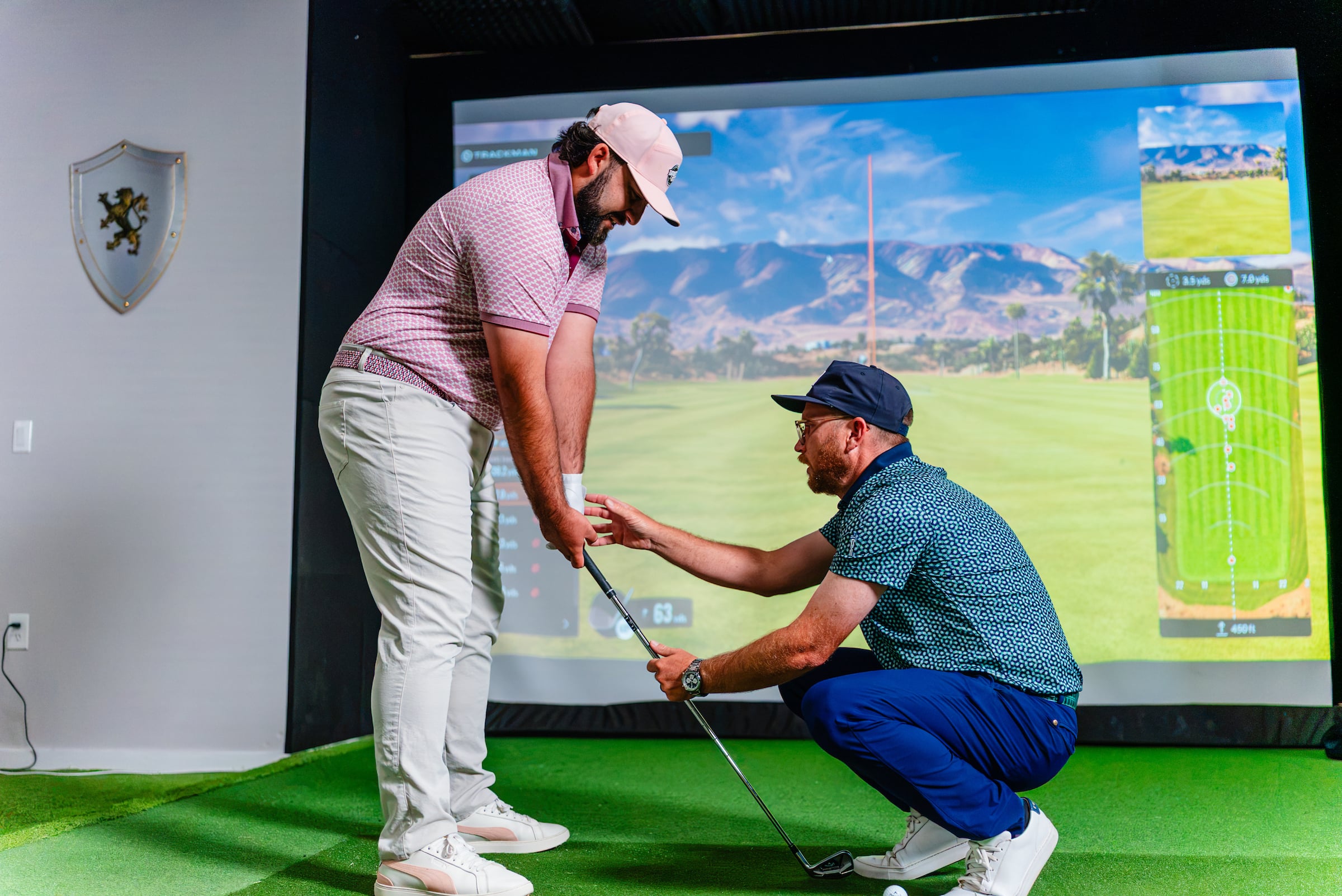 Male golf instructor with male student working on golf swing in simulator