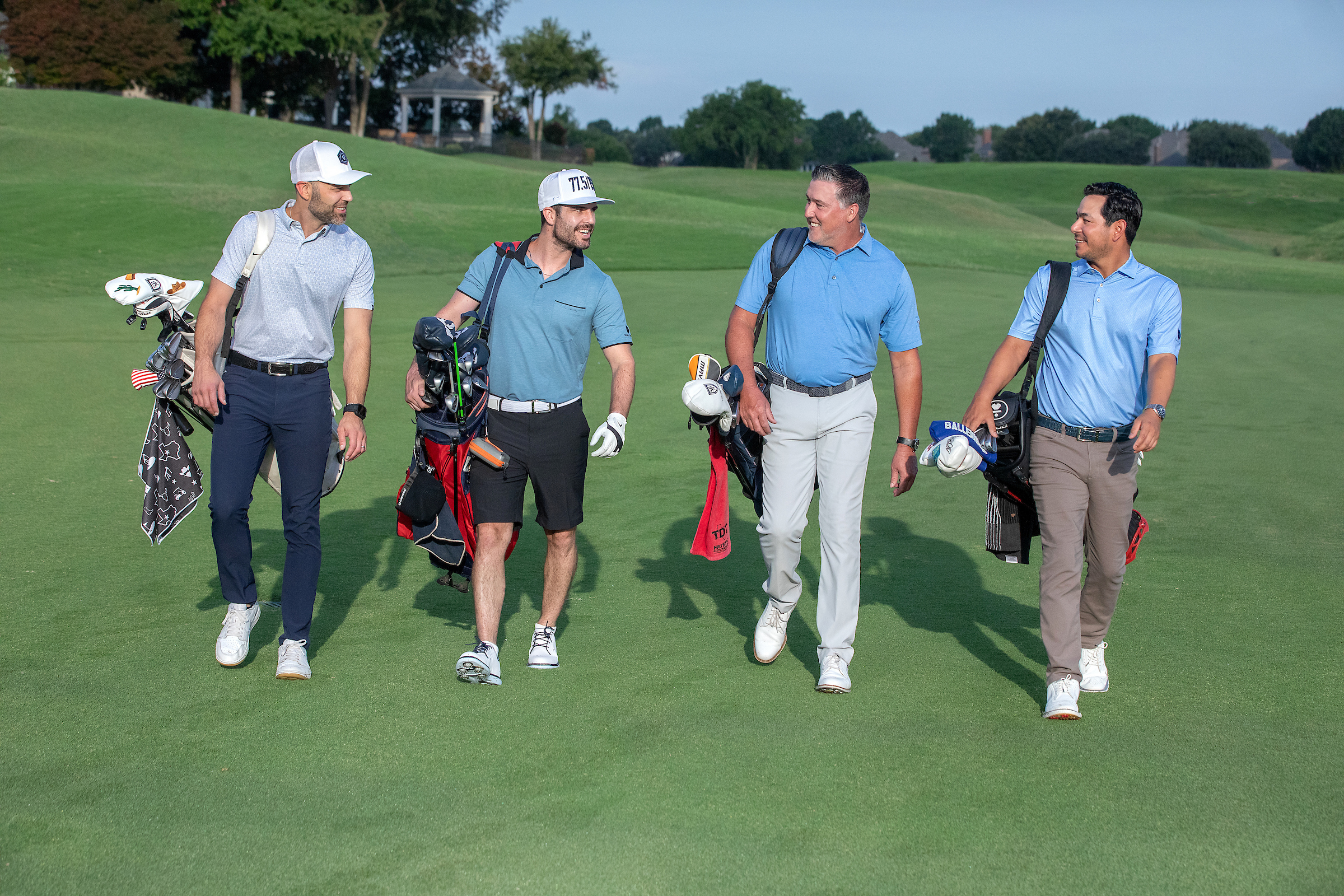 4 men walking on the golf course with their bags