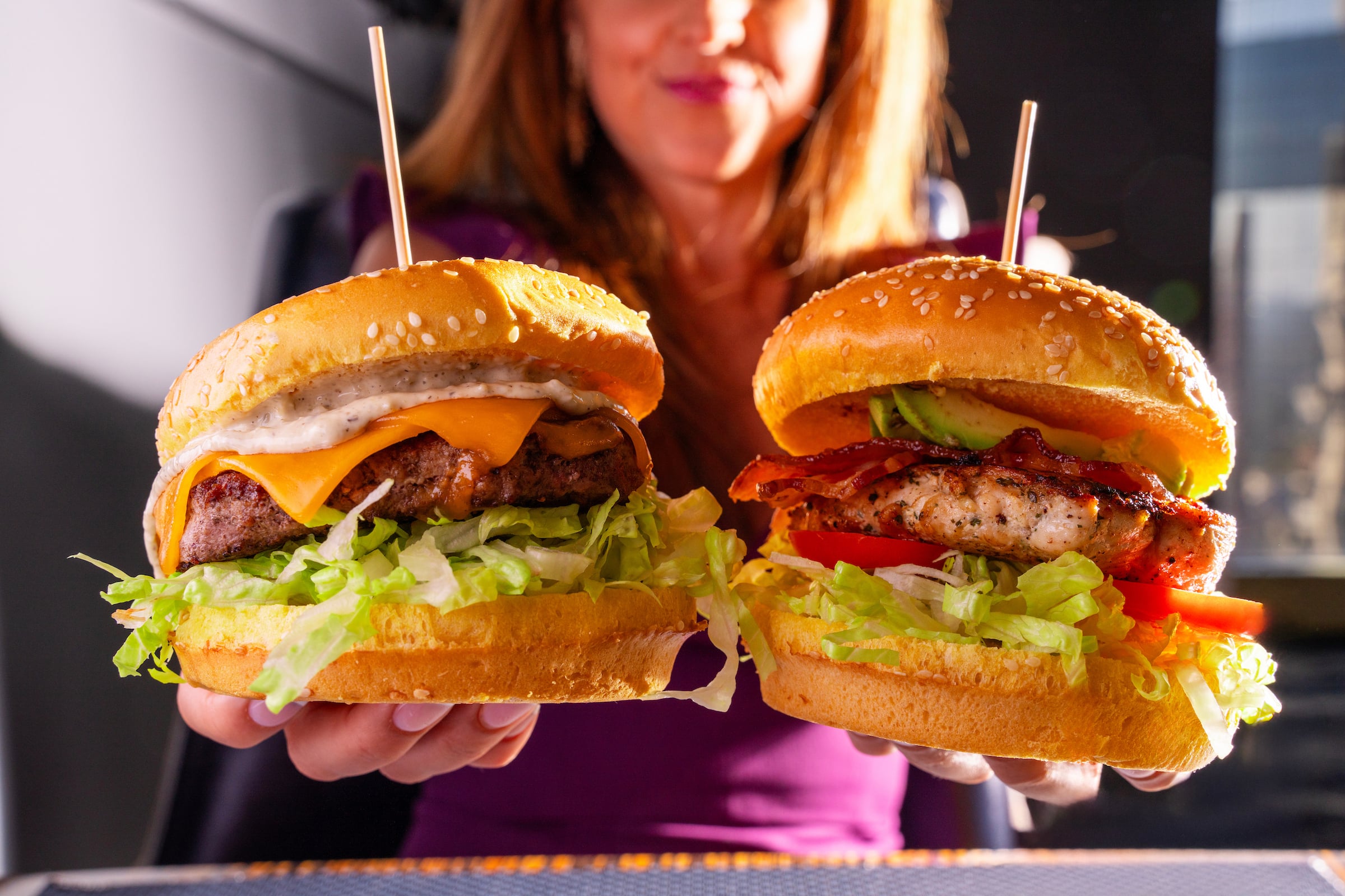 Two burgers held by a woman