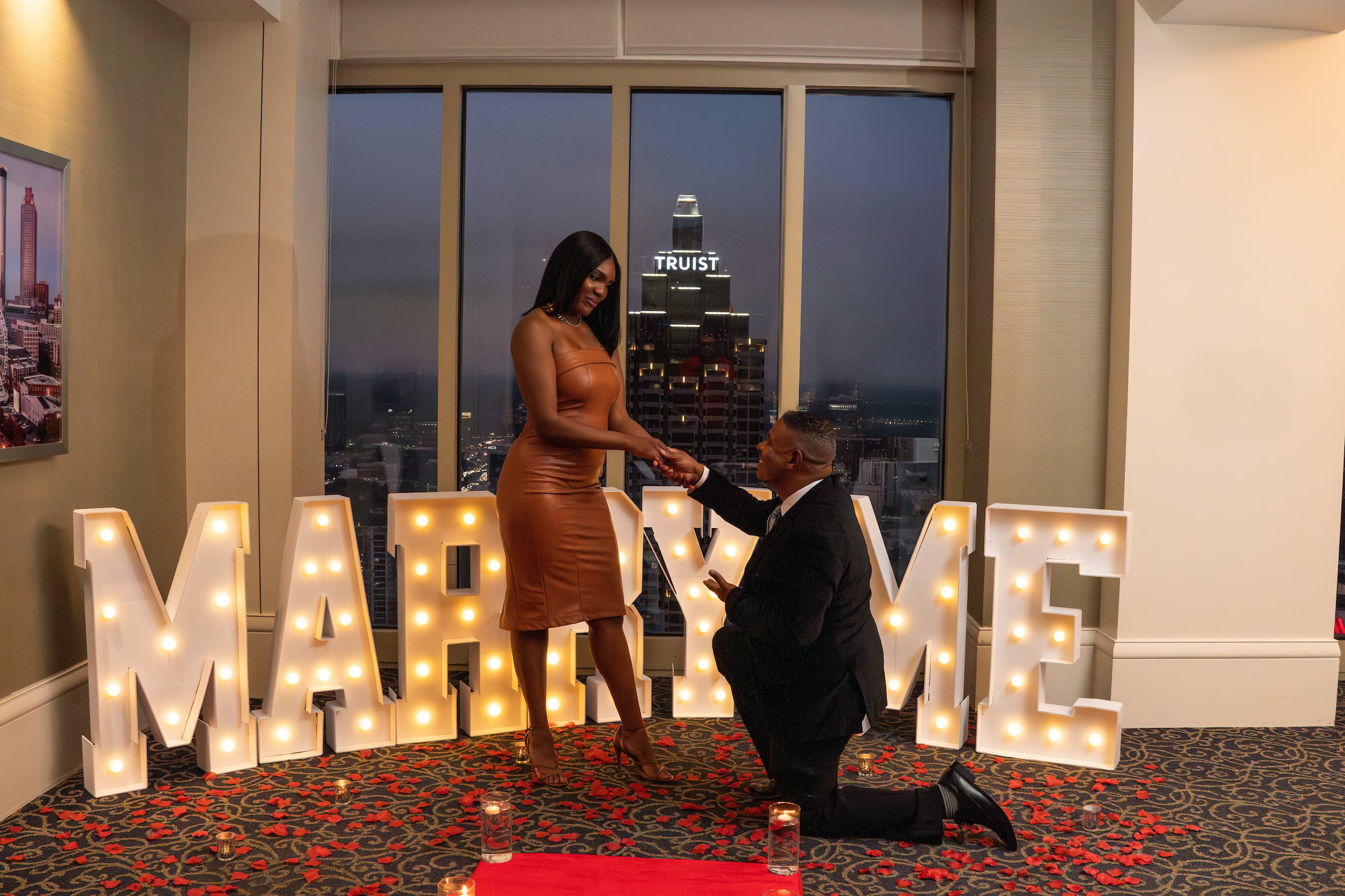 Man proposing to woman in front of Marry Me sign