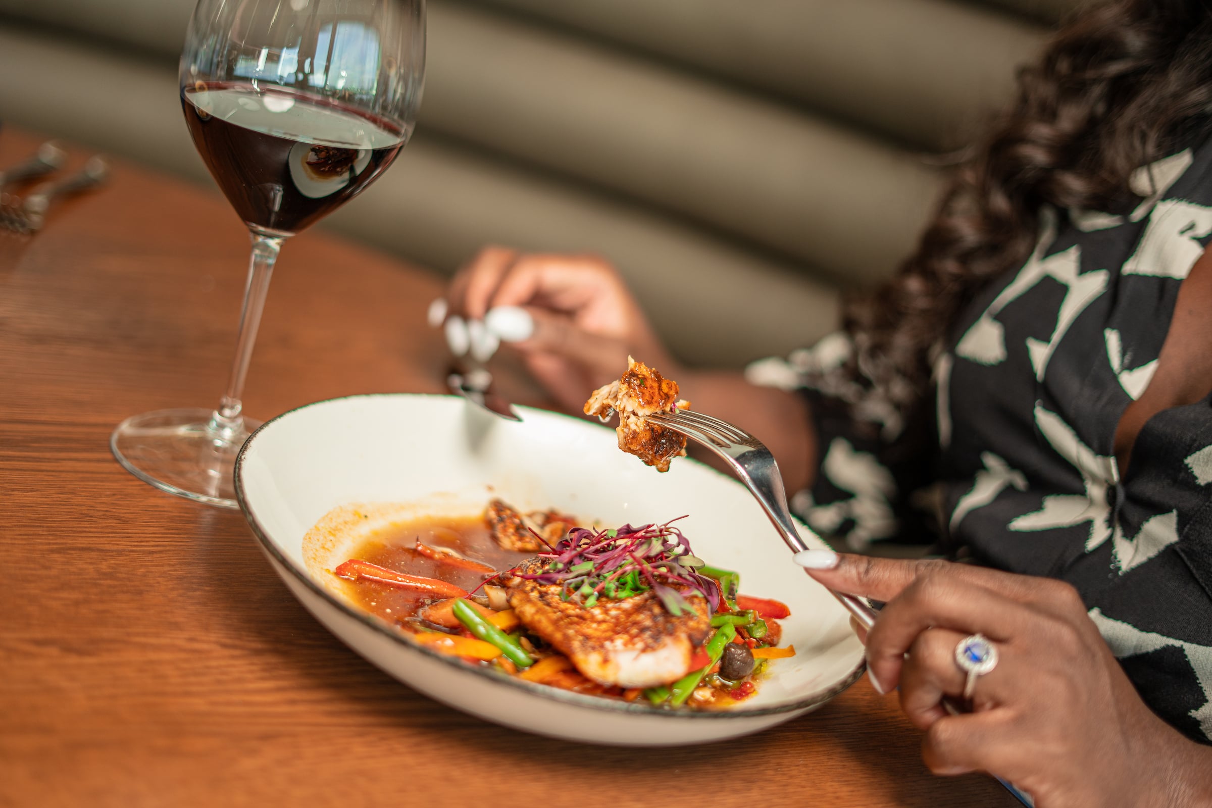 Woman eating a plate of food & a glass of wine