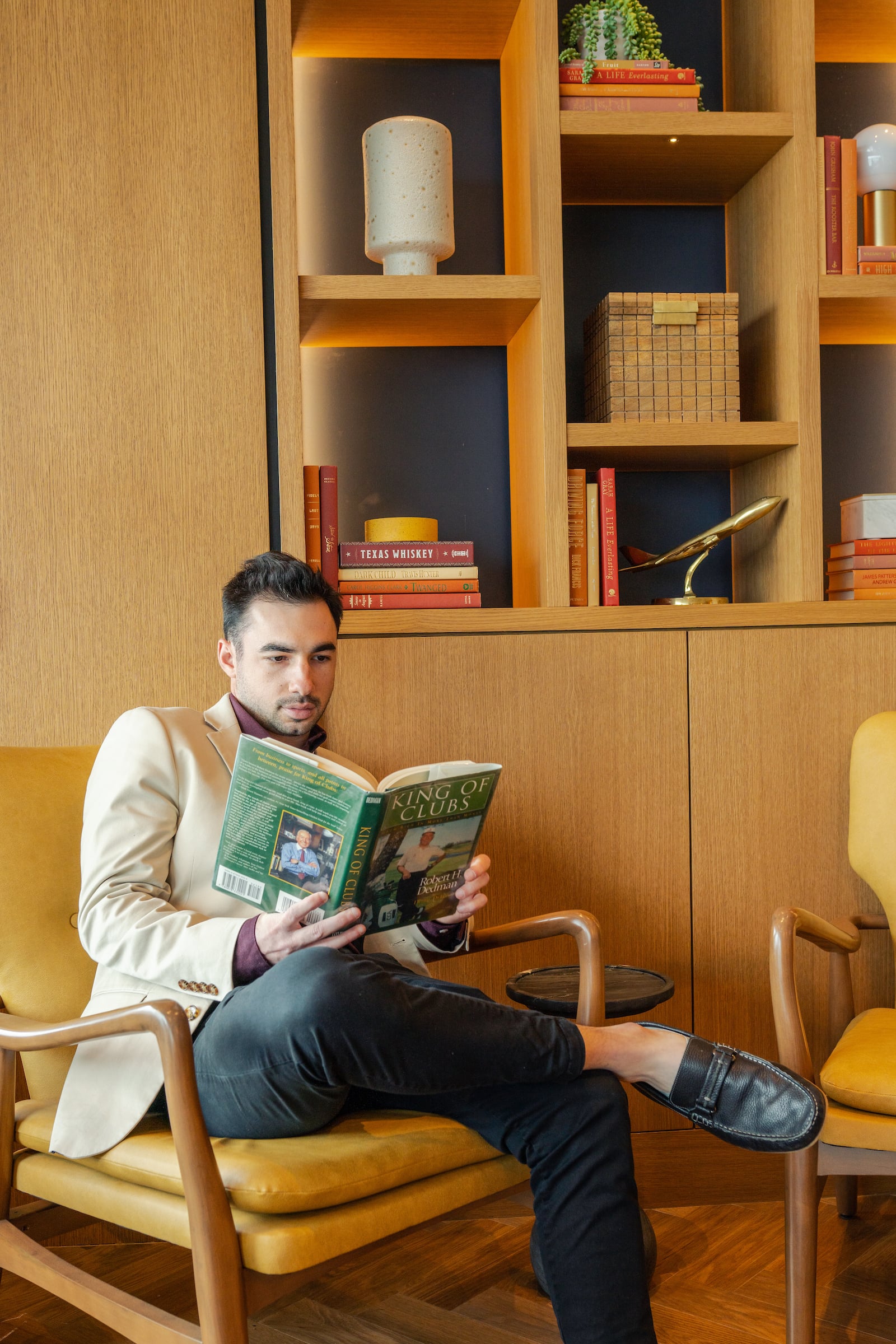 Man sitting in chair reading a book in The Constellation Club Lounge