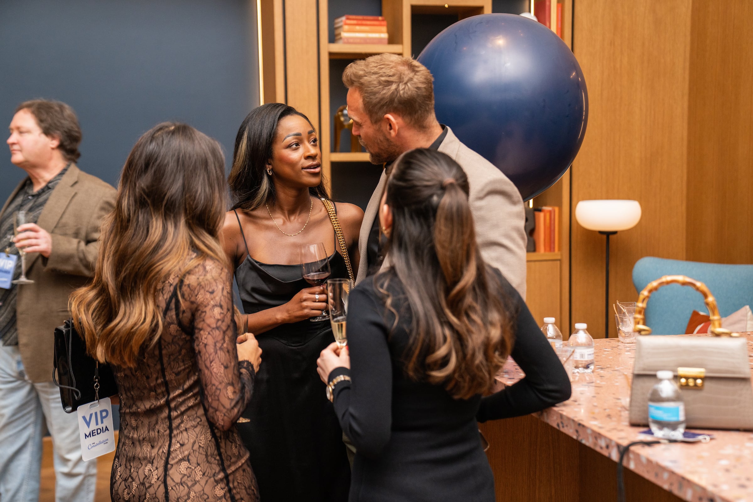 One man & 3 women talking at a private event
