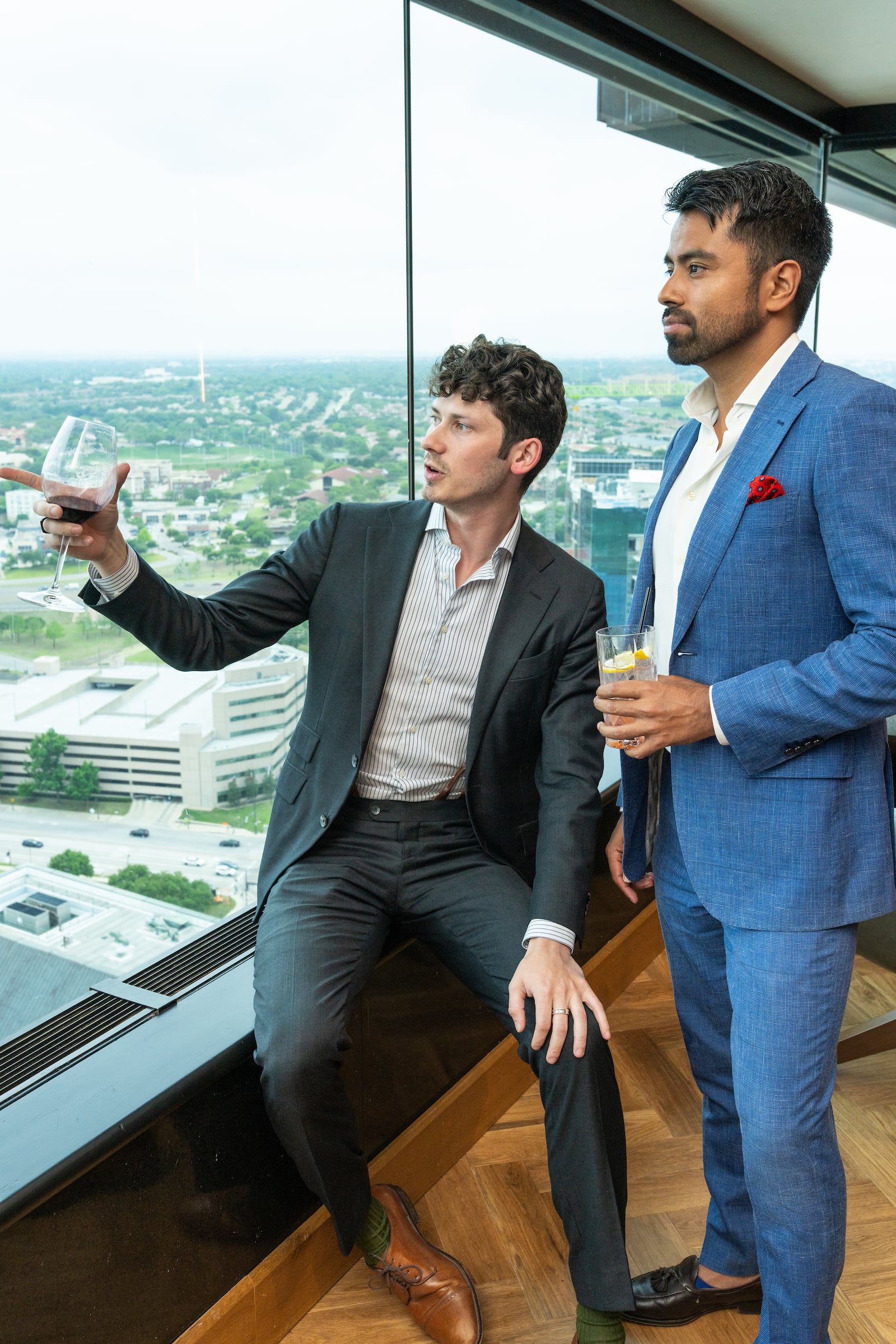 two men with drinks looking out the window