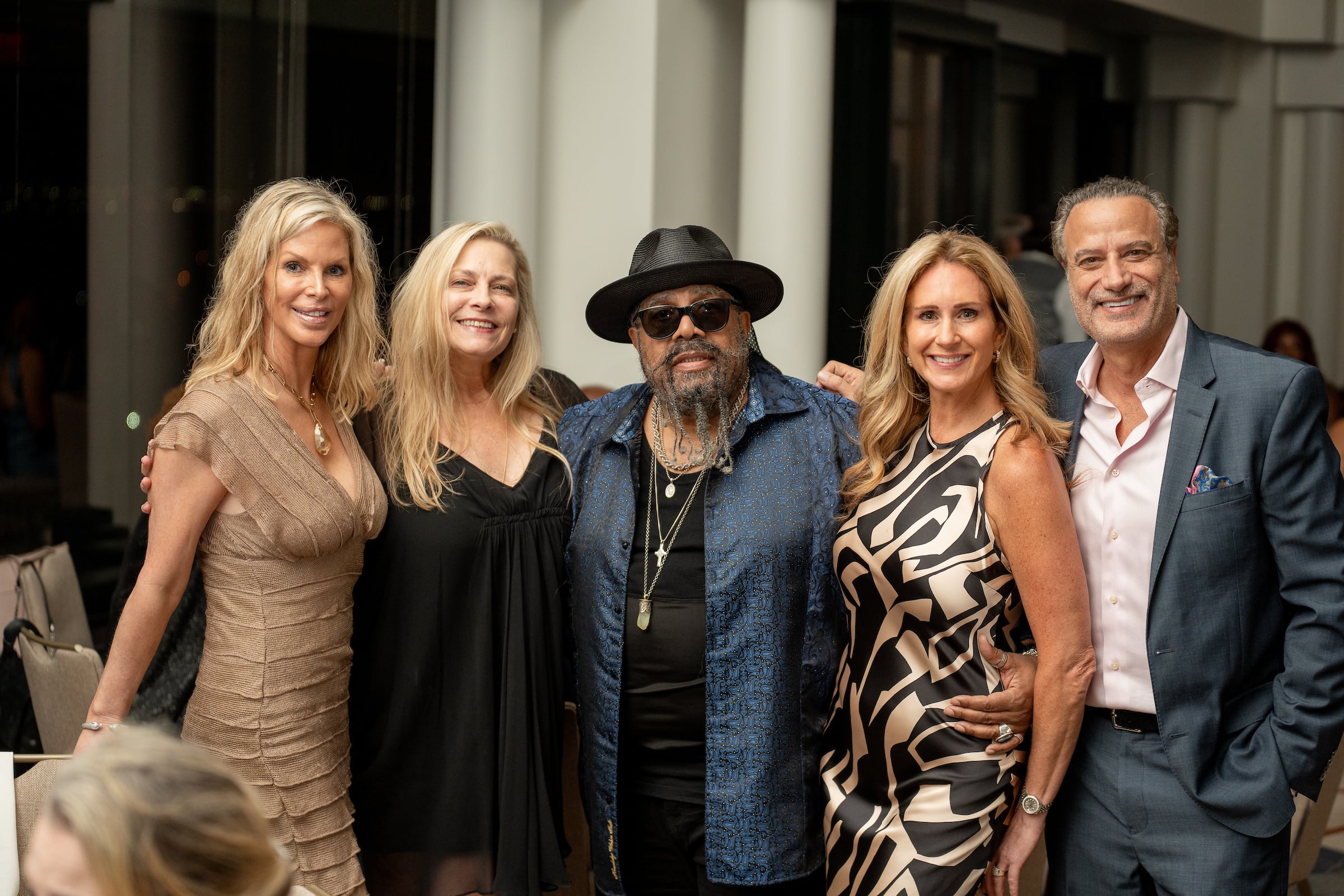 three women & two men posing for an image at a private event
