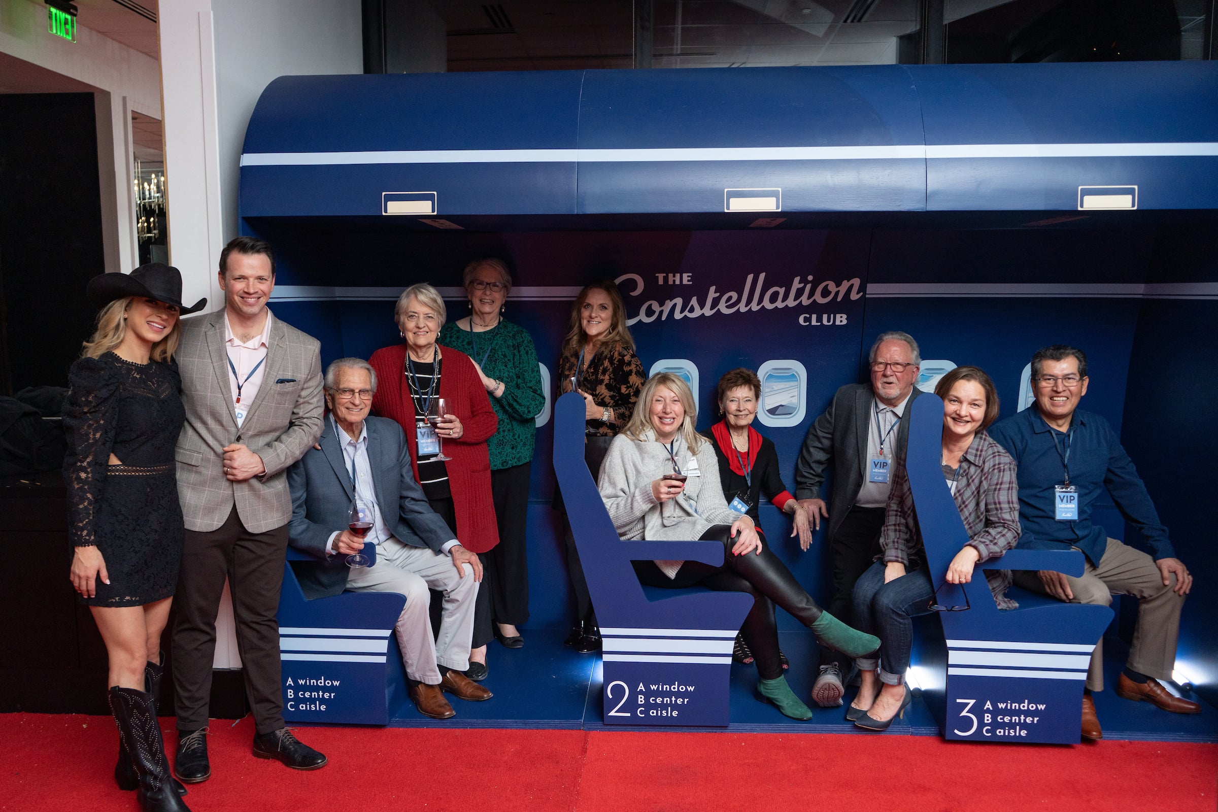 large group at a private event seated in a plane posing for a picture
