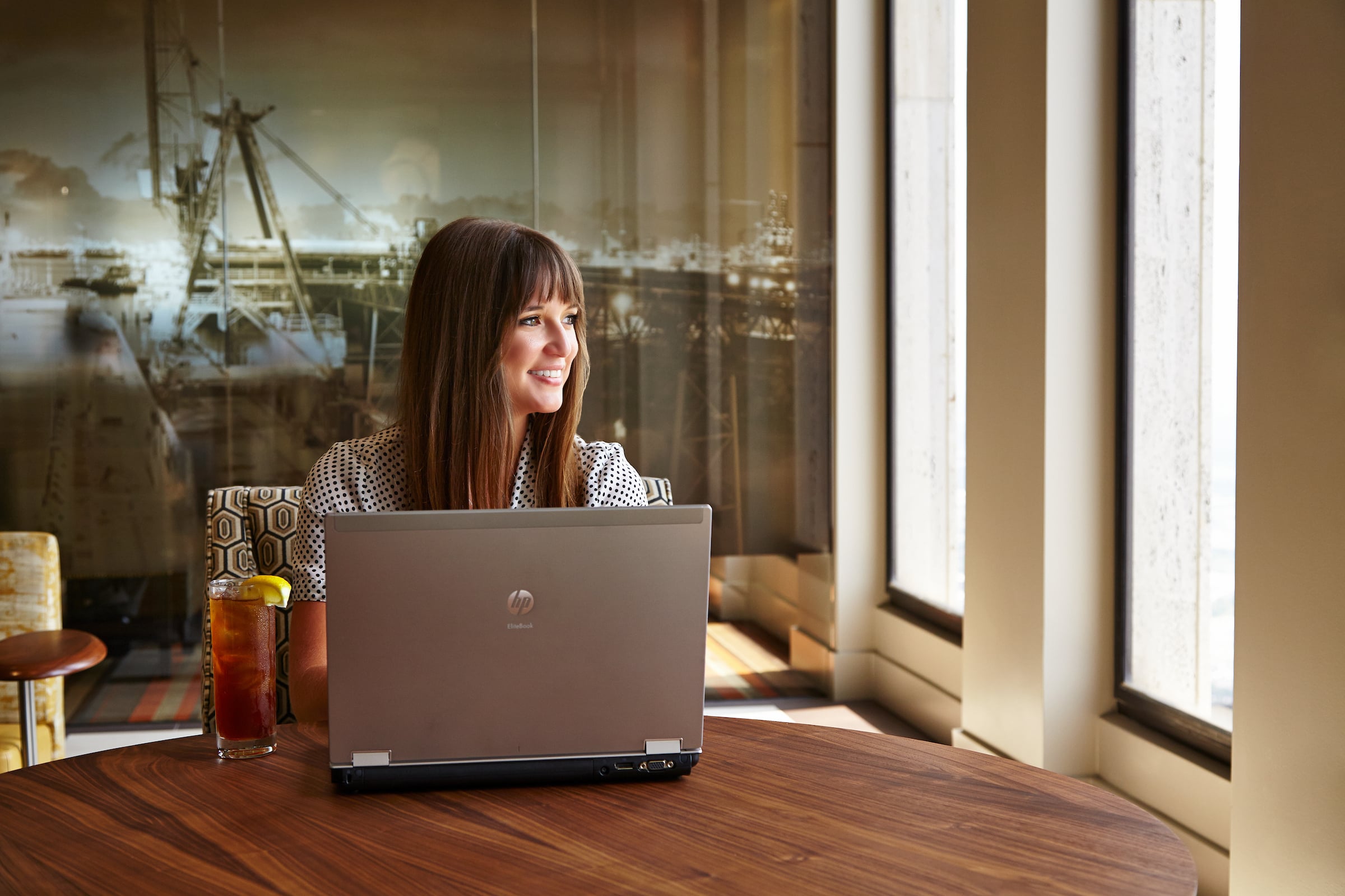 Woman seated at table with her computer & a glass of iced tea