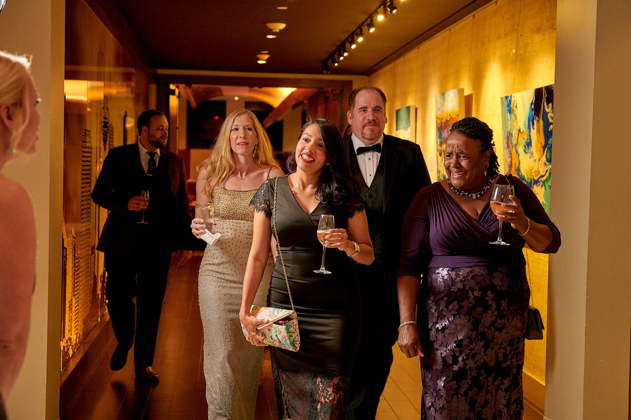 Group of 3 women & 2 men dressed for private event & walking down hall at The Houston Club