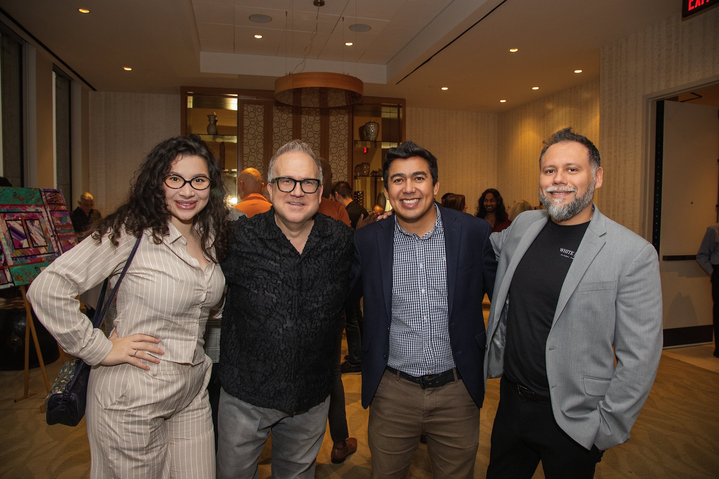 Three men & a woman posing at a private event