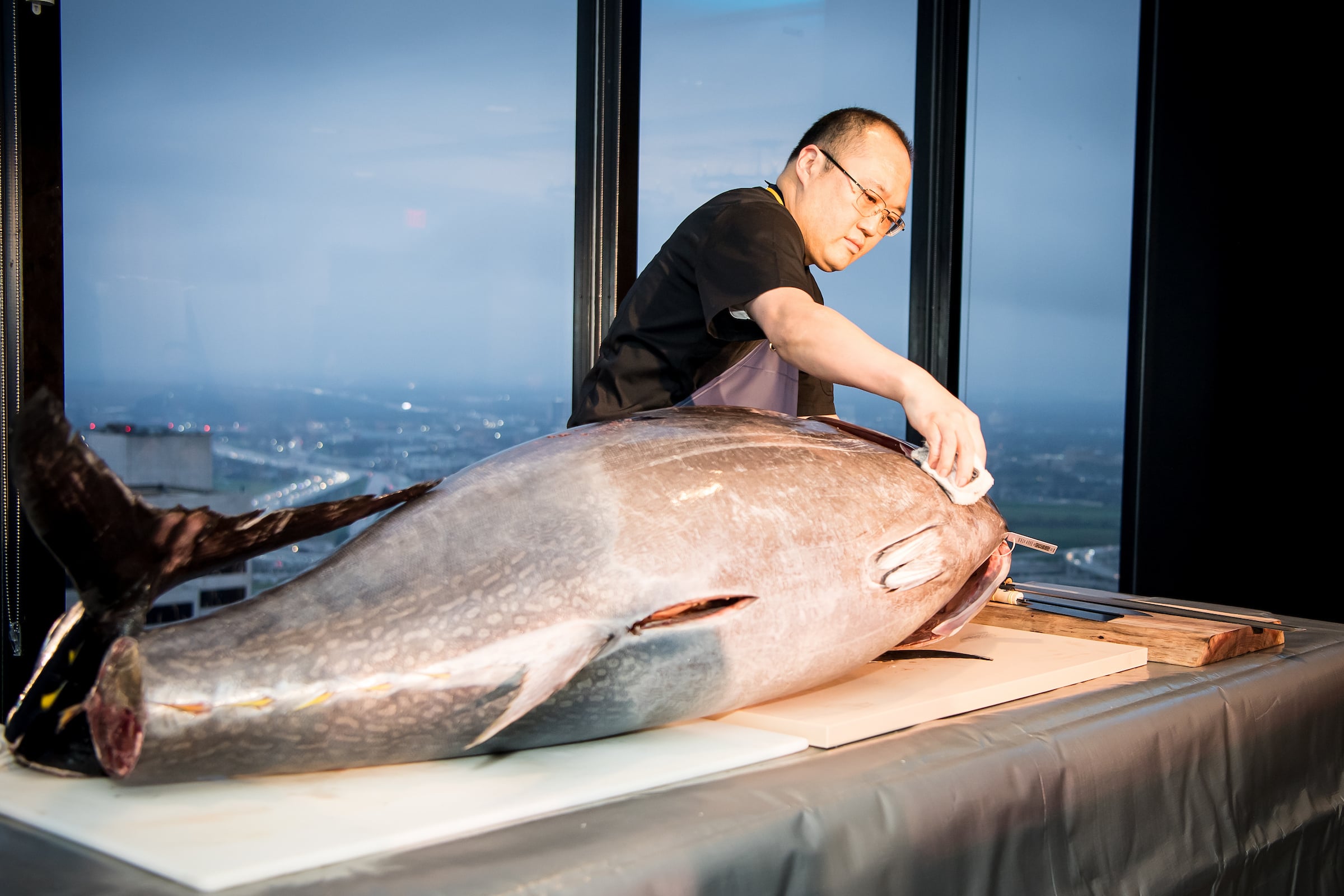 Tower Club Dallas Chef Joon Lee preparing large fish