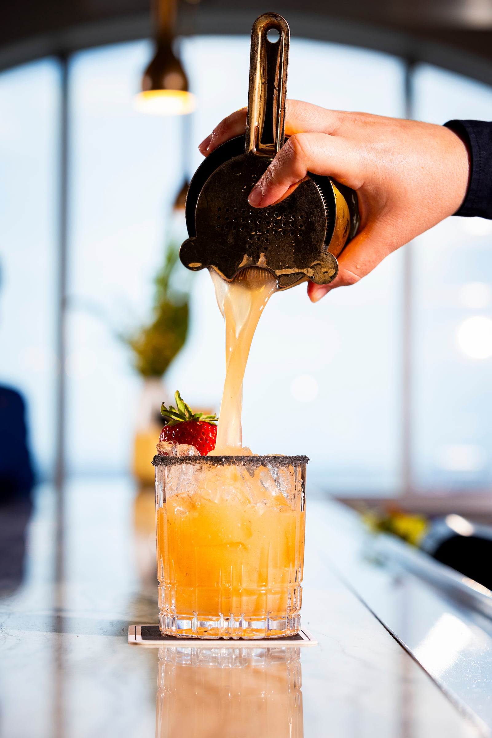 Cocktail being poured in a highball glass