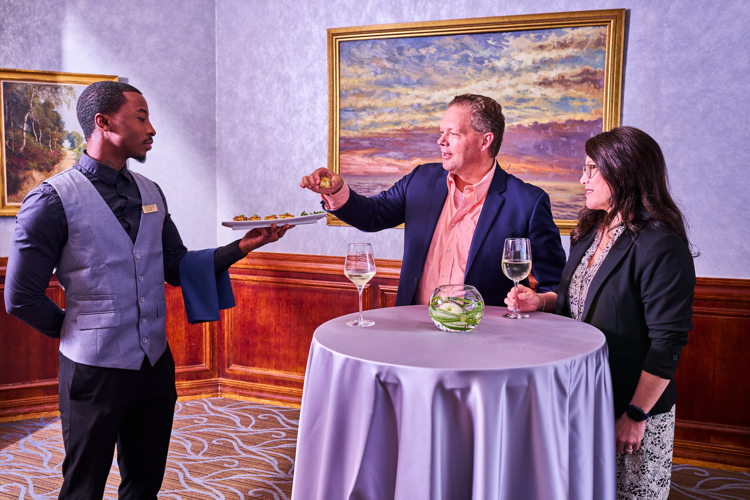 Male server offering appetizer tray to a couple at a private event