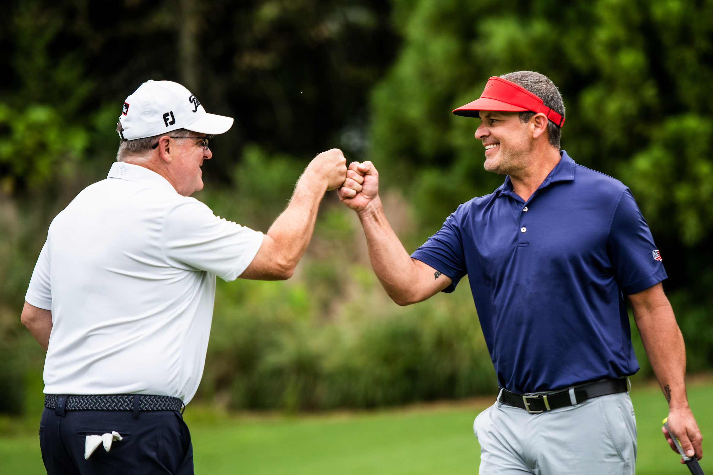 2 men bumping fists after a good shot on the golf course