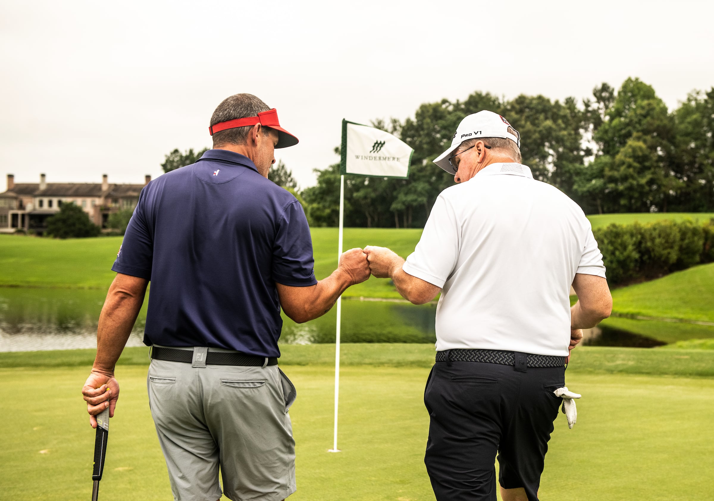 2 male golfers getting their golf balls from the hole