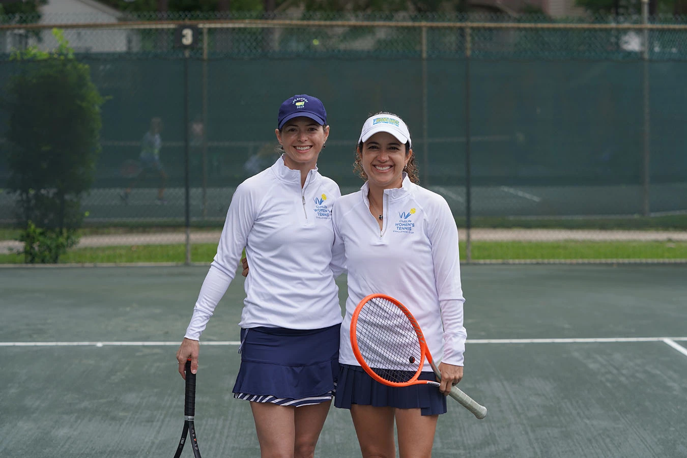 women posing for a photo on a tennis court